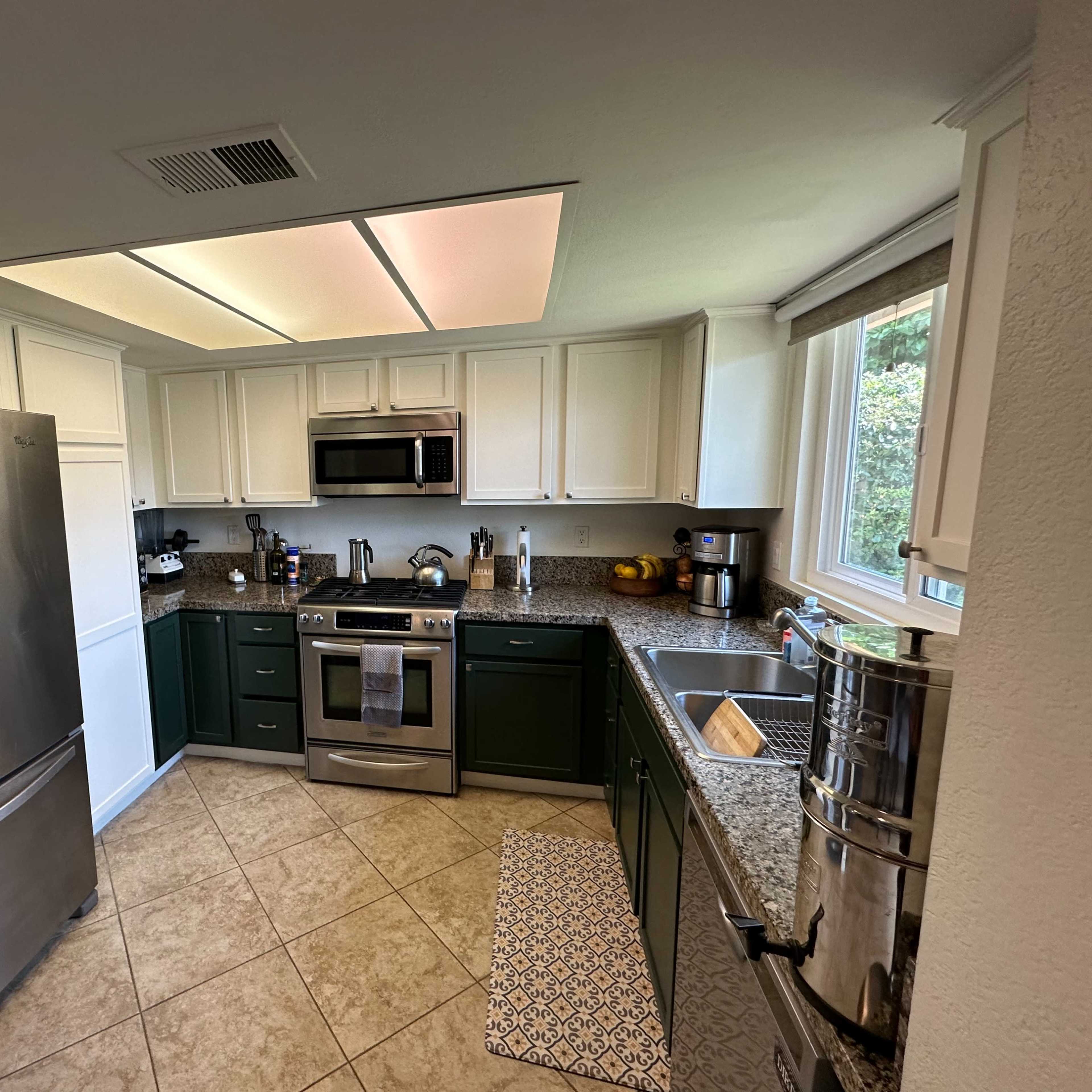 A modern kitchen featuring stainless steel appliances, white cabinets, and a granite countertop with a spacious layout.