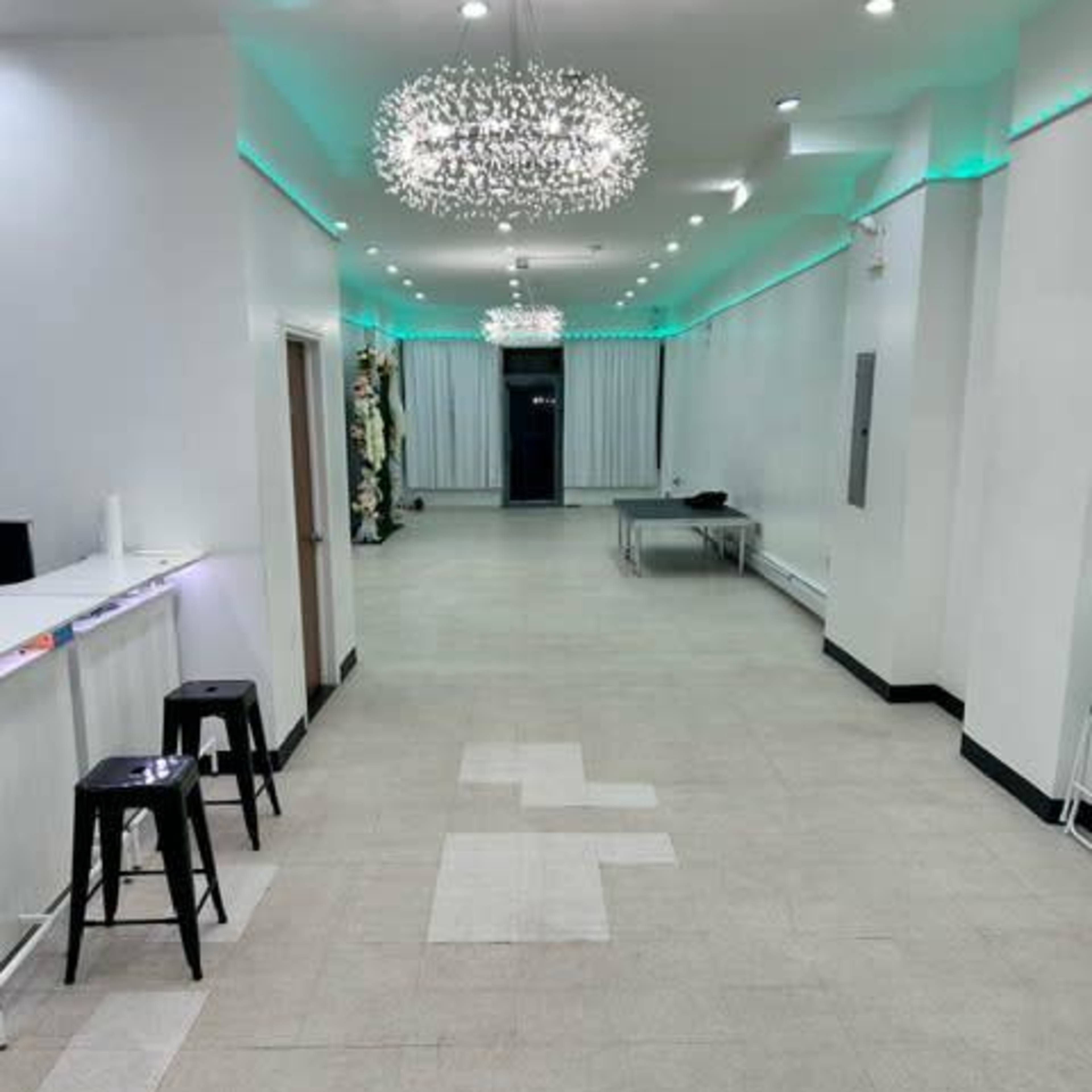 A spacious, well-lit interior with a long corridor, black stools, and decorative light fixtures on the ceiling.