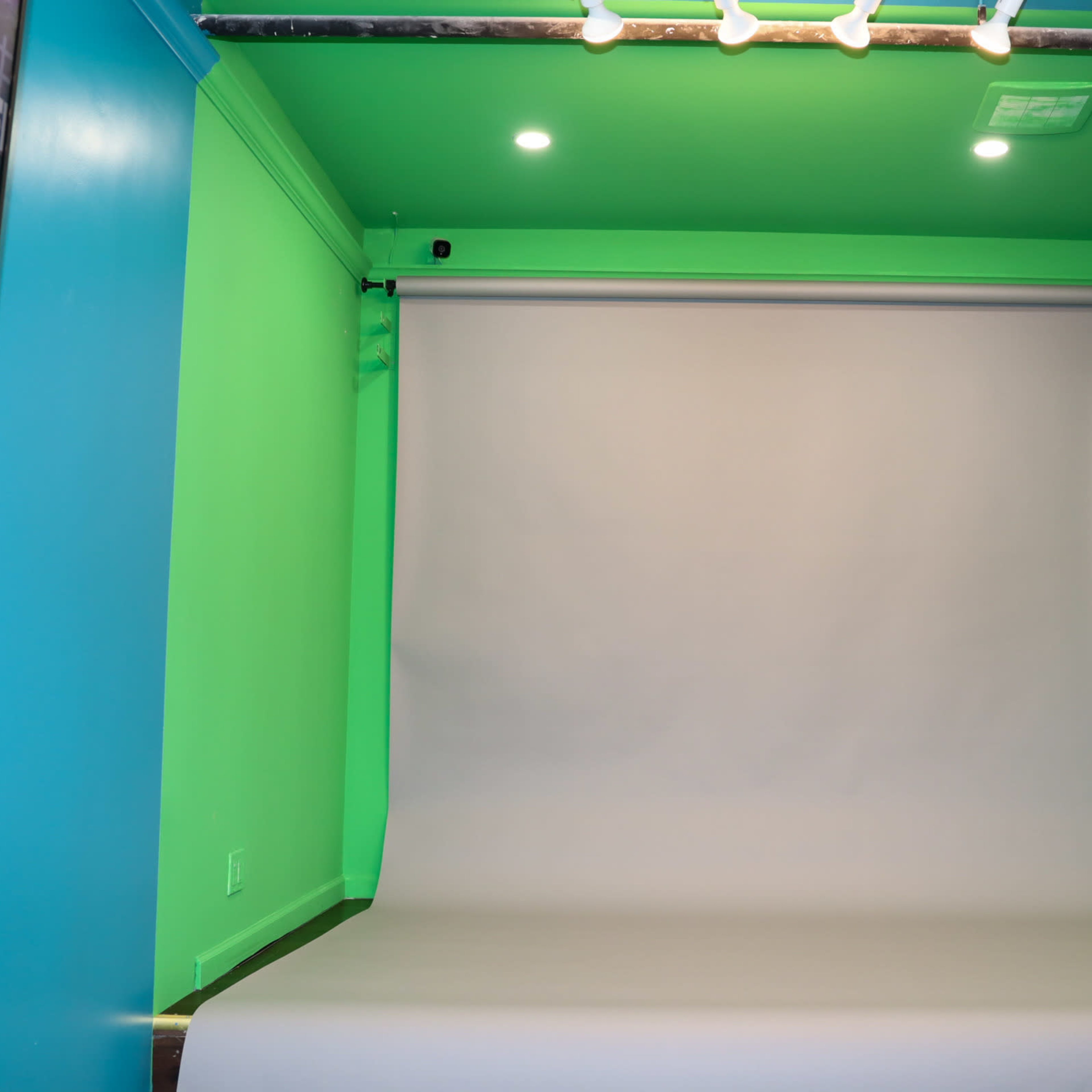 A photography studio with a green wall and a light gray backdrop on a roll.
