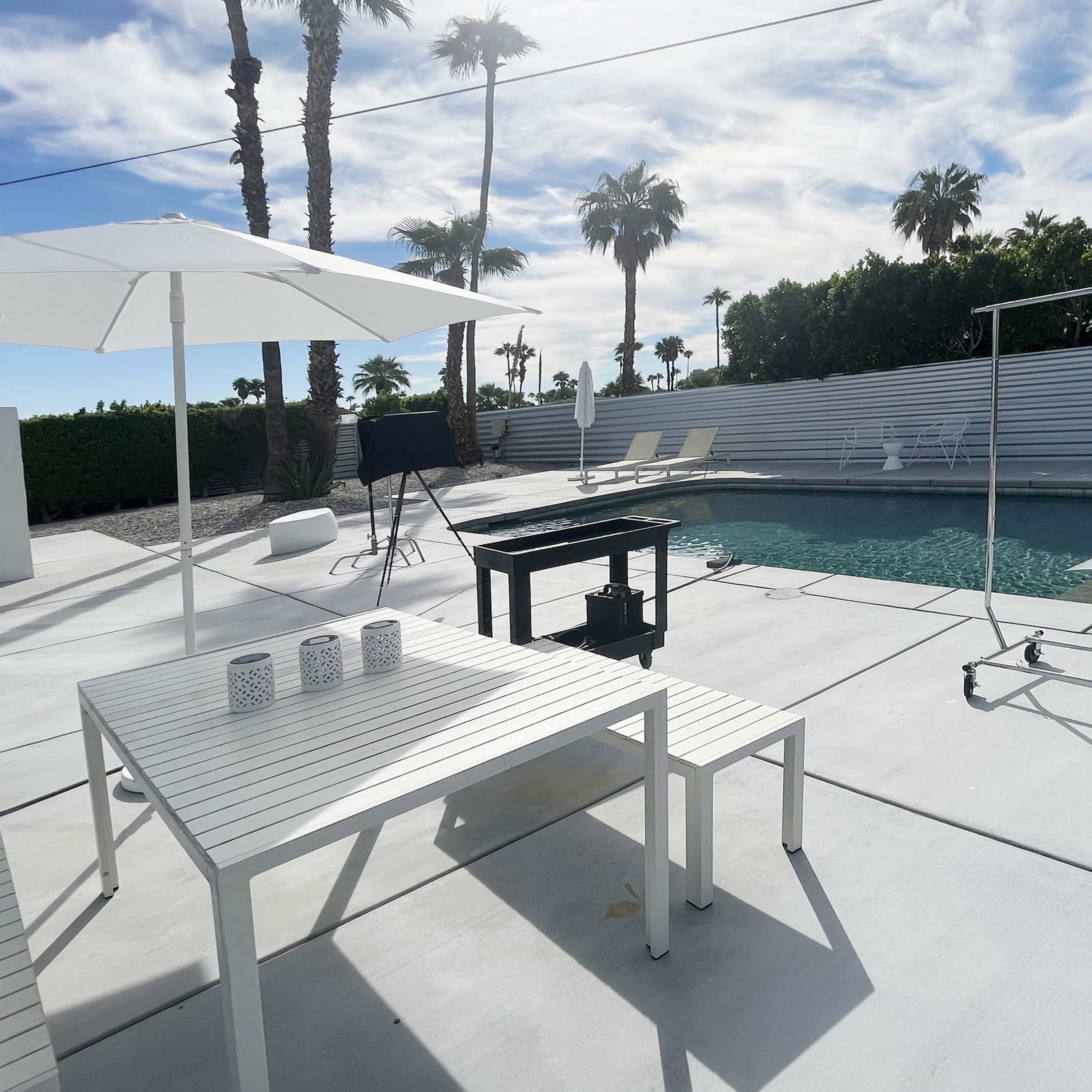 A modern, one-story house surrounded by palm trees and gravel landscaping in a desert setting.