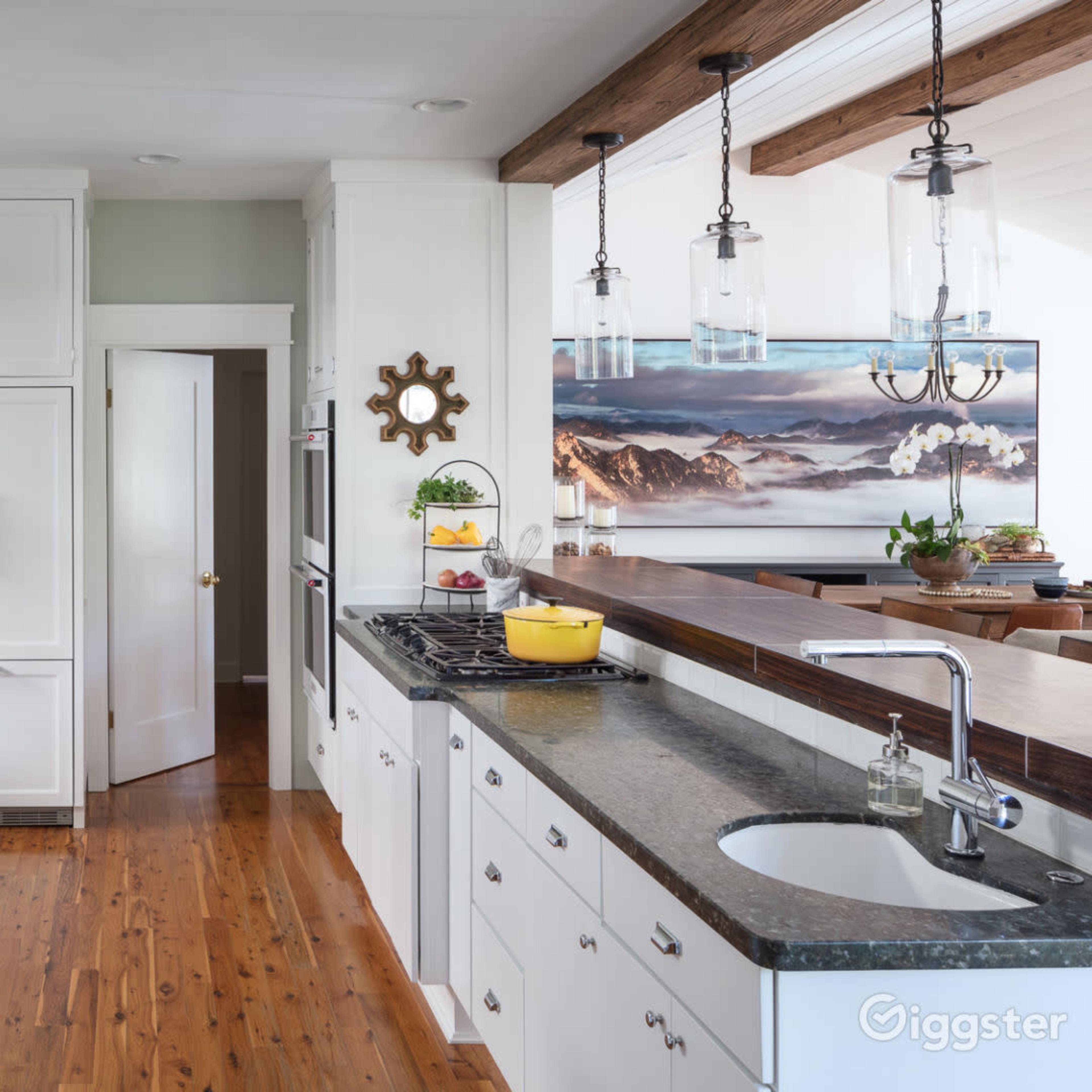 A well-organized kitchen with white cabinets, dark countertops, and a large window that offers a view of a mountain landscape.