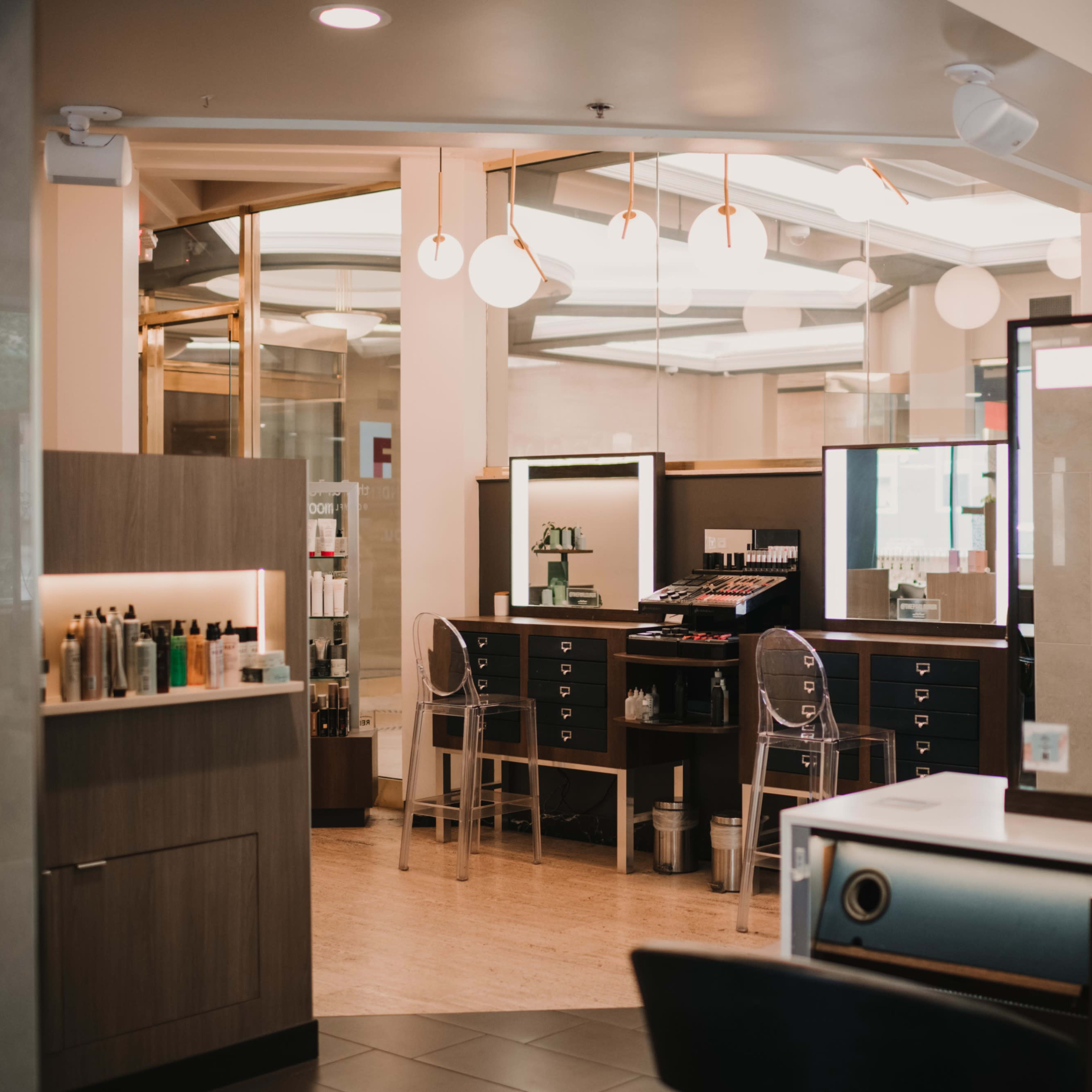 A modern salon interior featuring styling stations, mirrors, and product displays.