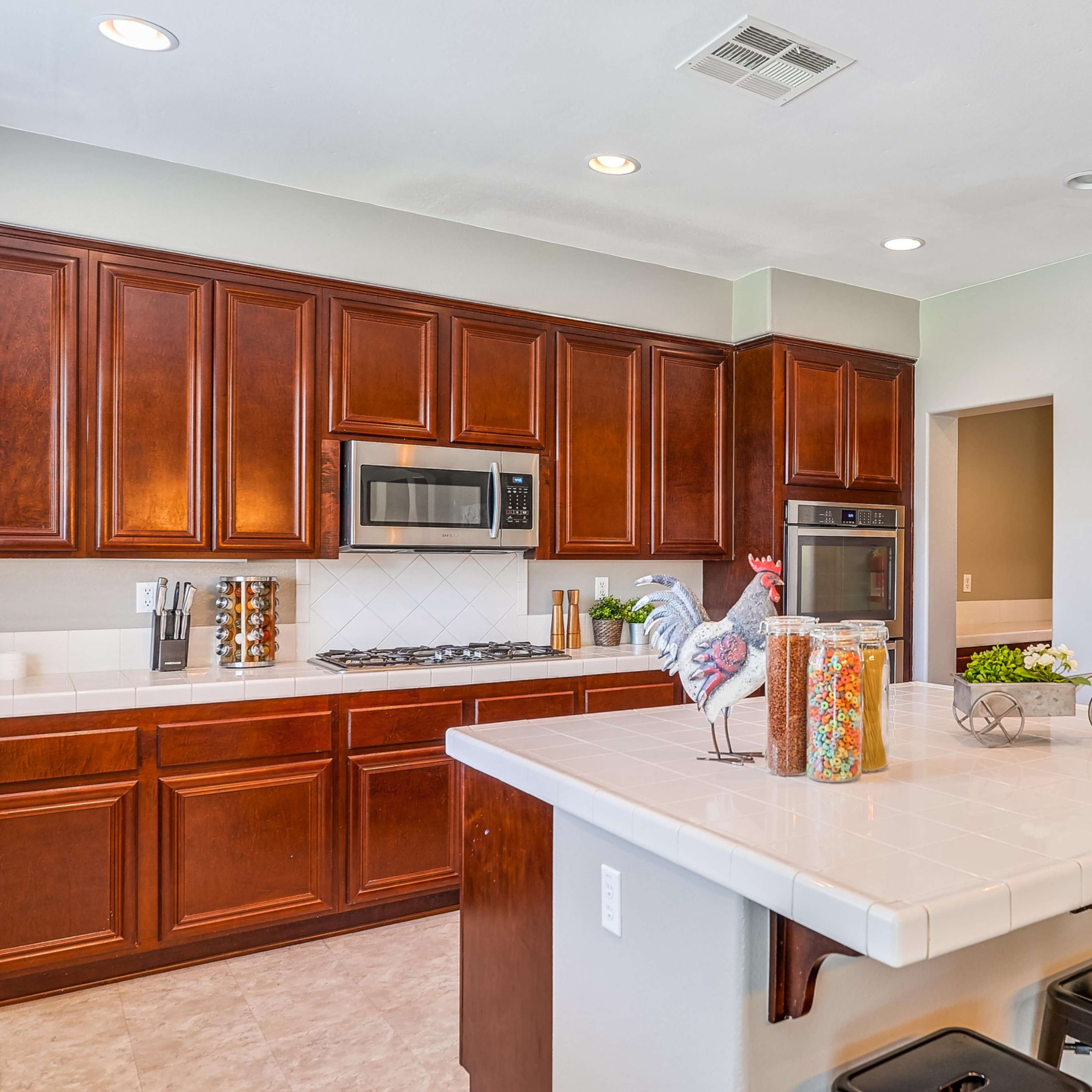 A modern kitchen with dark wooden cabinetry, stainless steel appliances, and a central island with bar stools.