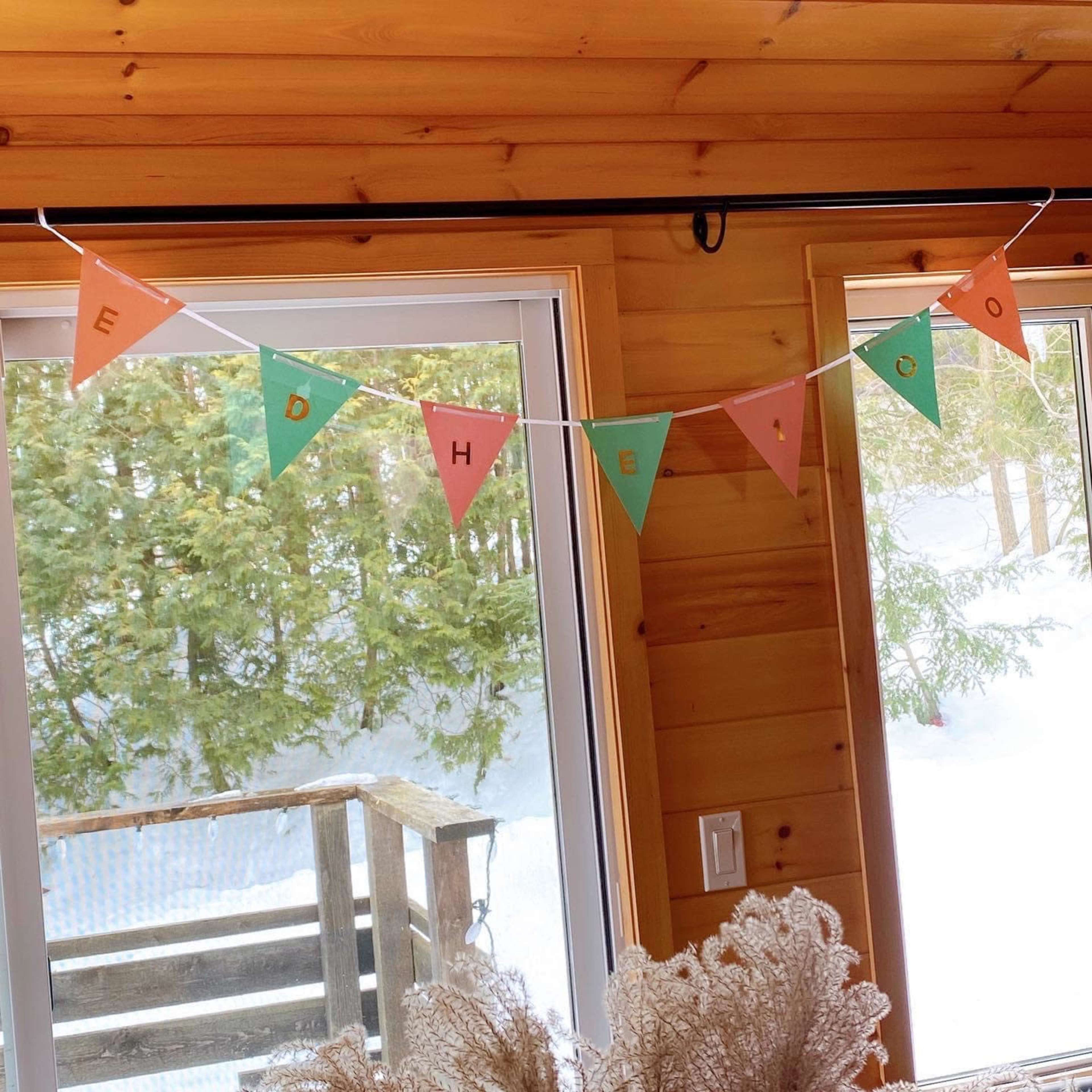 A string of decorative triangular banners hangs across a window, featuring letters and colors in alternating patterns.