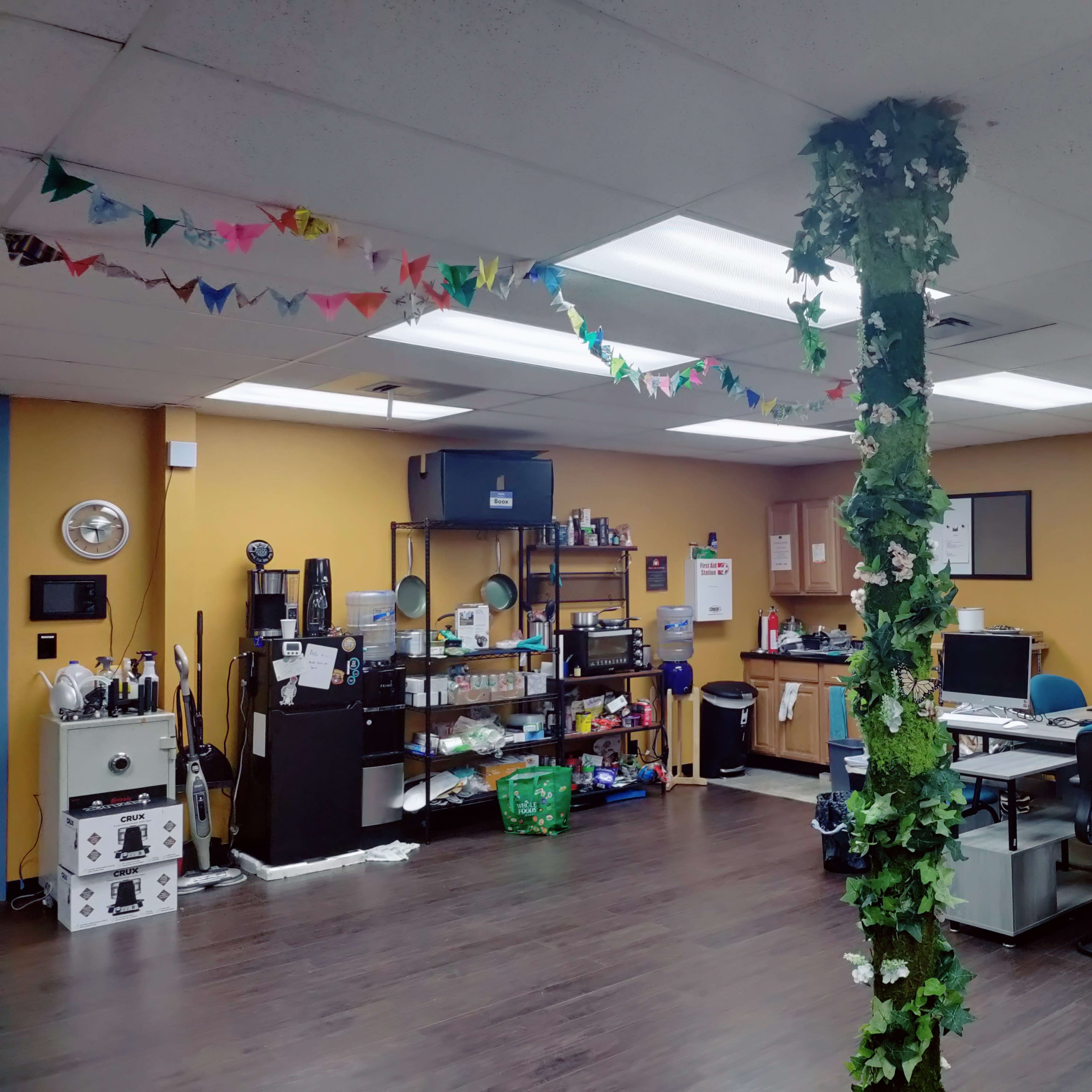 An office space with workstations, storage shelves, and decorative garlands along the ceiling.