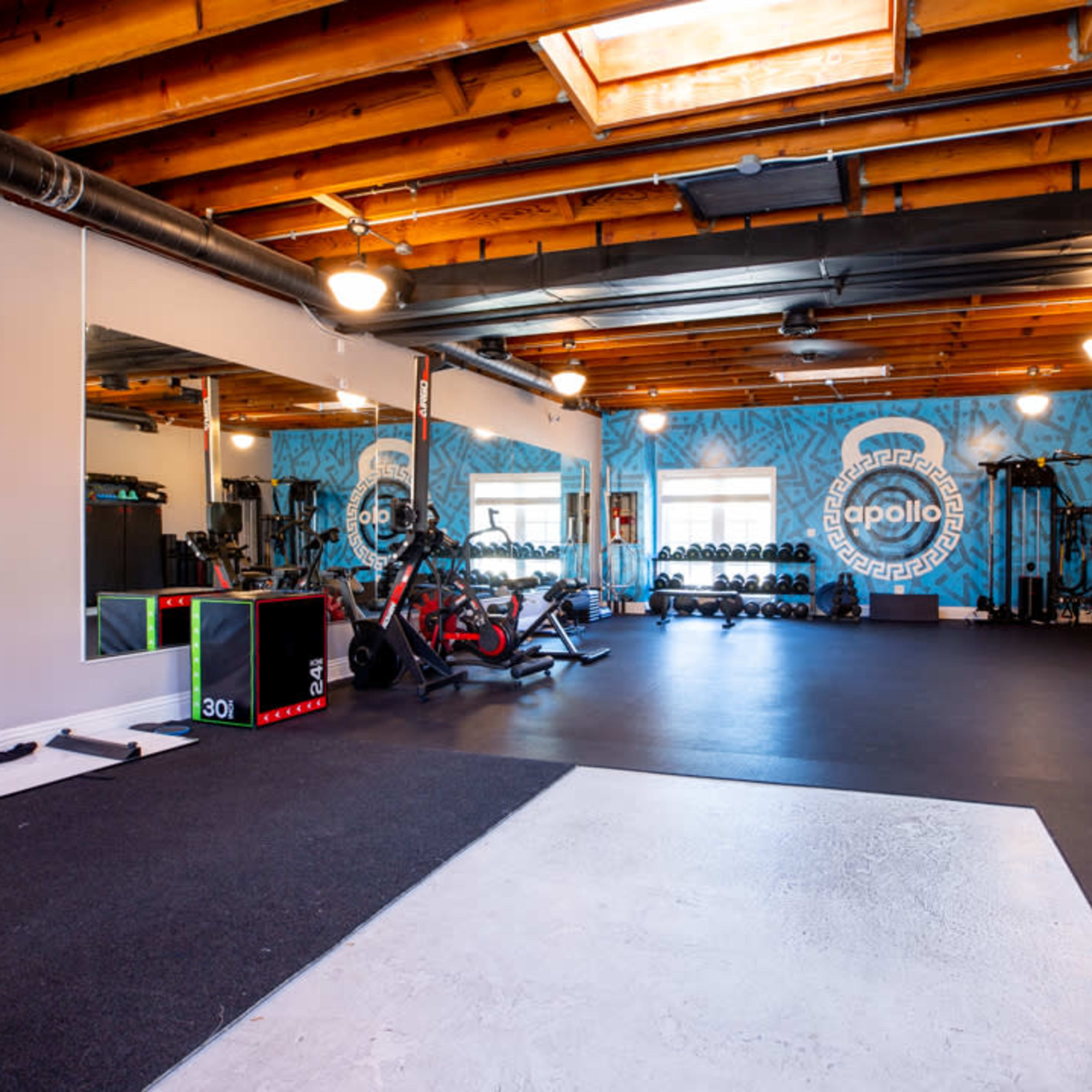 A spacious gym with exercise equipment, including bikes and weights, and large mirrors on one wall.