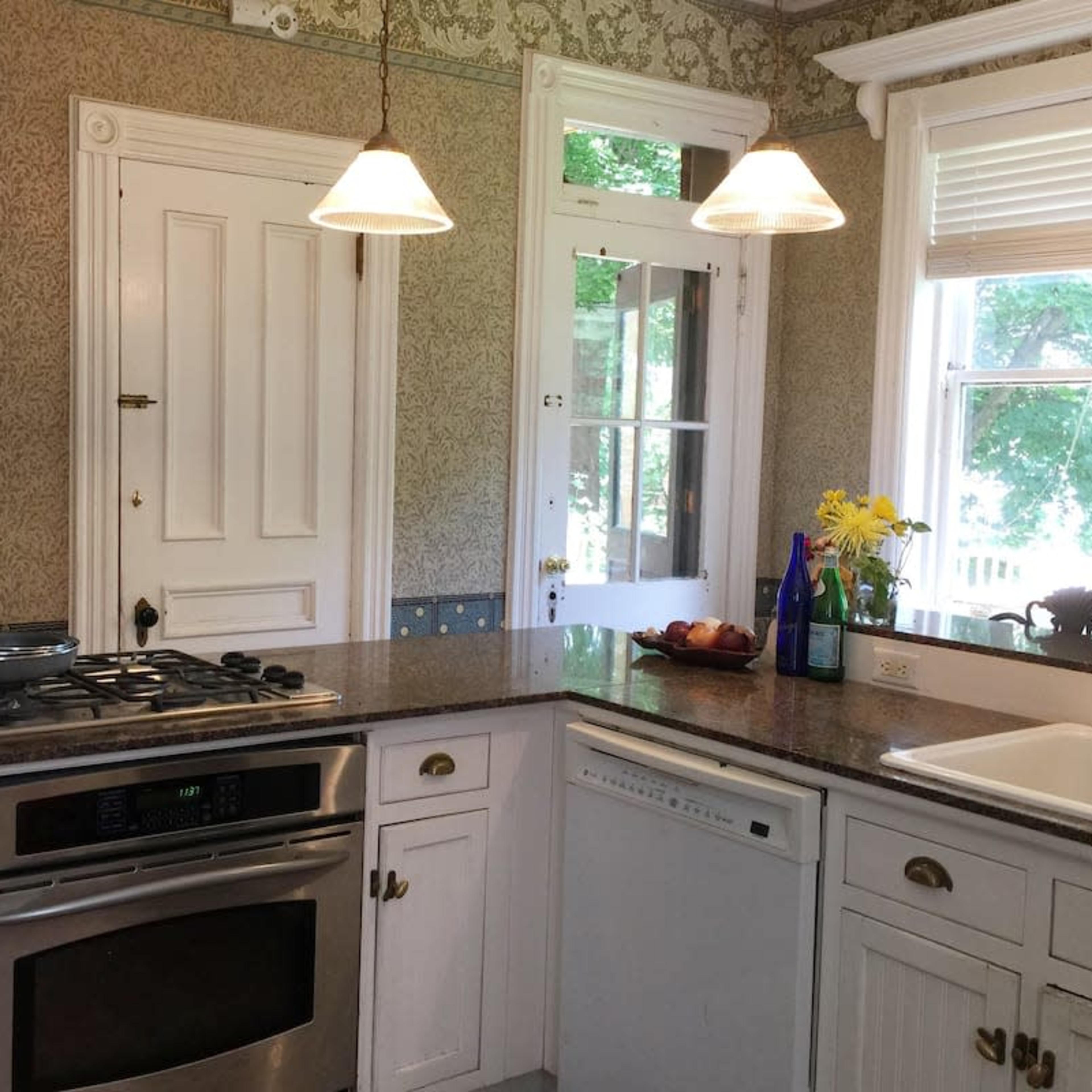 A bright kitchen with white cabinetry, a granite countertop, a gas stove, and a window that provides natural light.