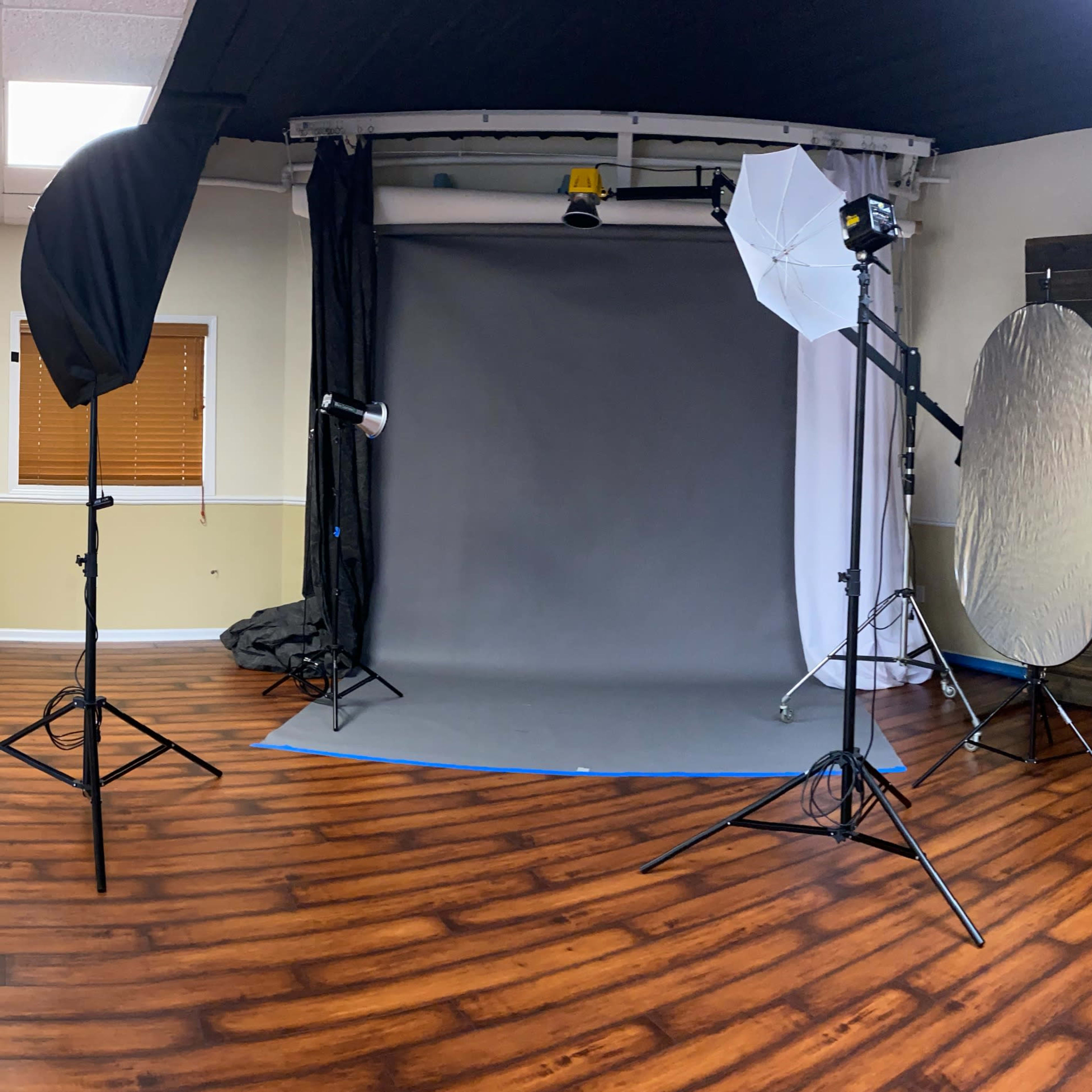 A photography studio with a backdrop, lighting equipment, and wooden walls.