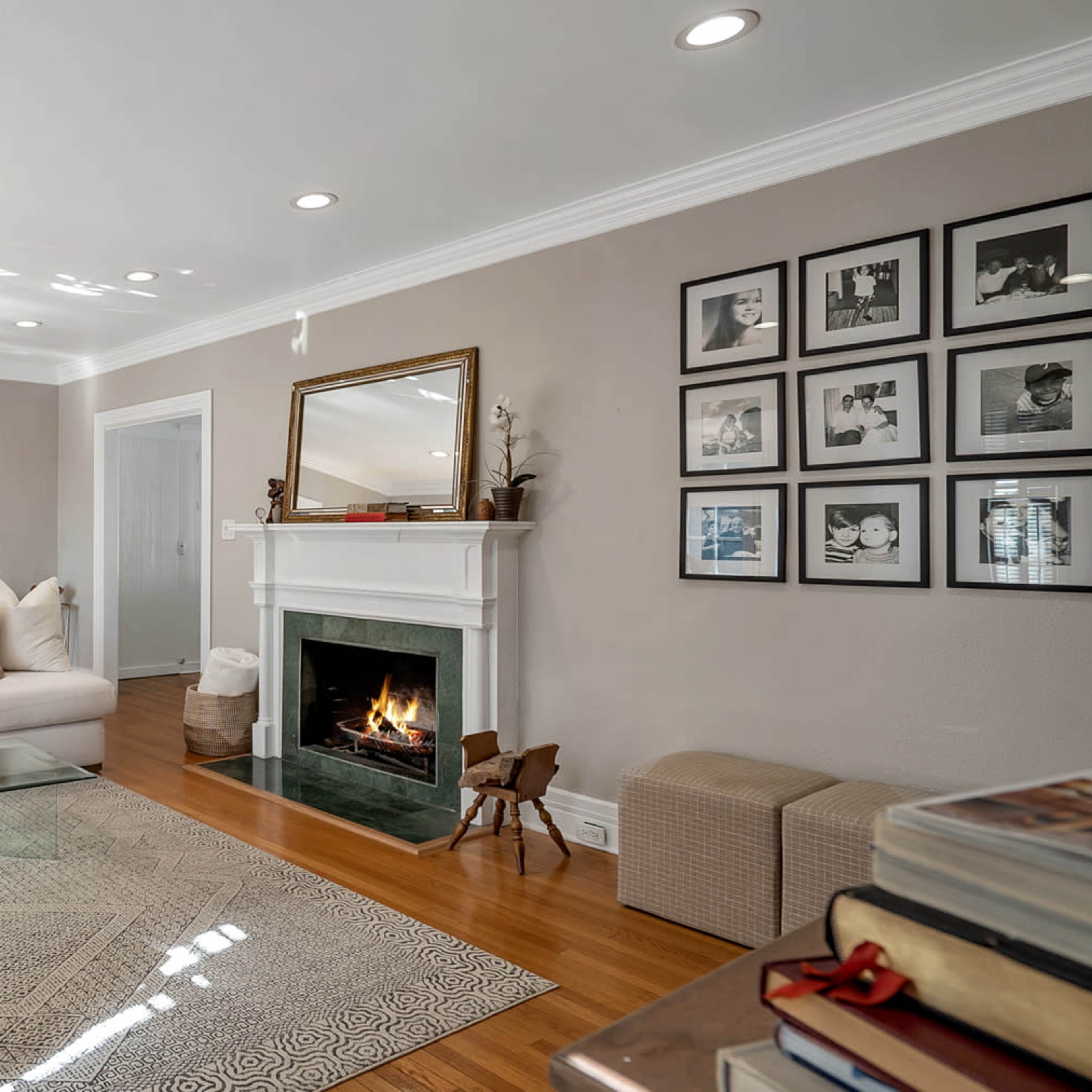 A living room with a white sofa, a fireplace, and a collection of framed black-and-white photographs on the wall.