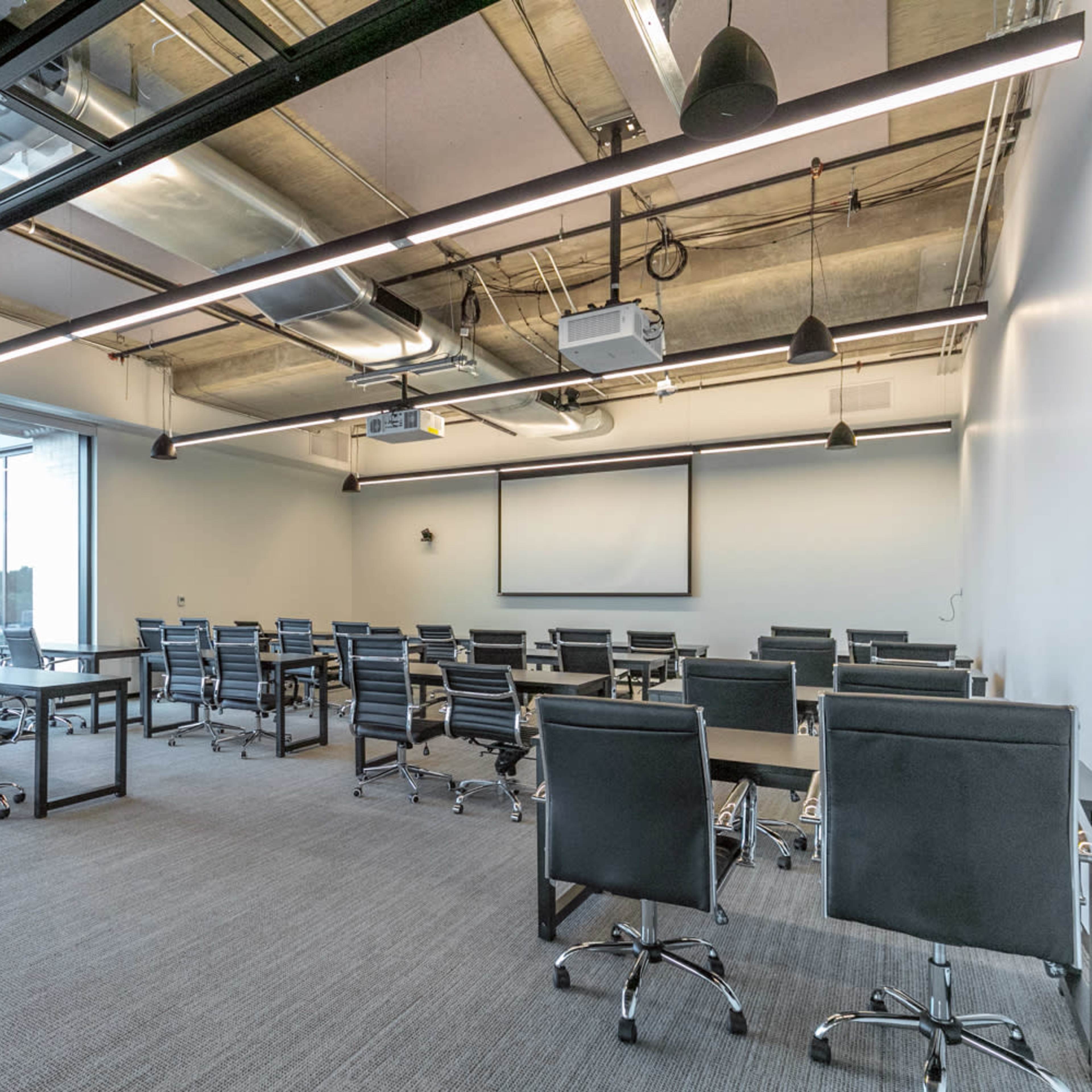 A modern conference room with several tables arranged for meetings and large windows letting in natural light.