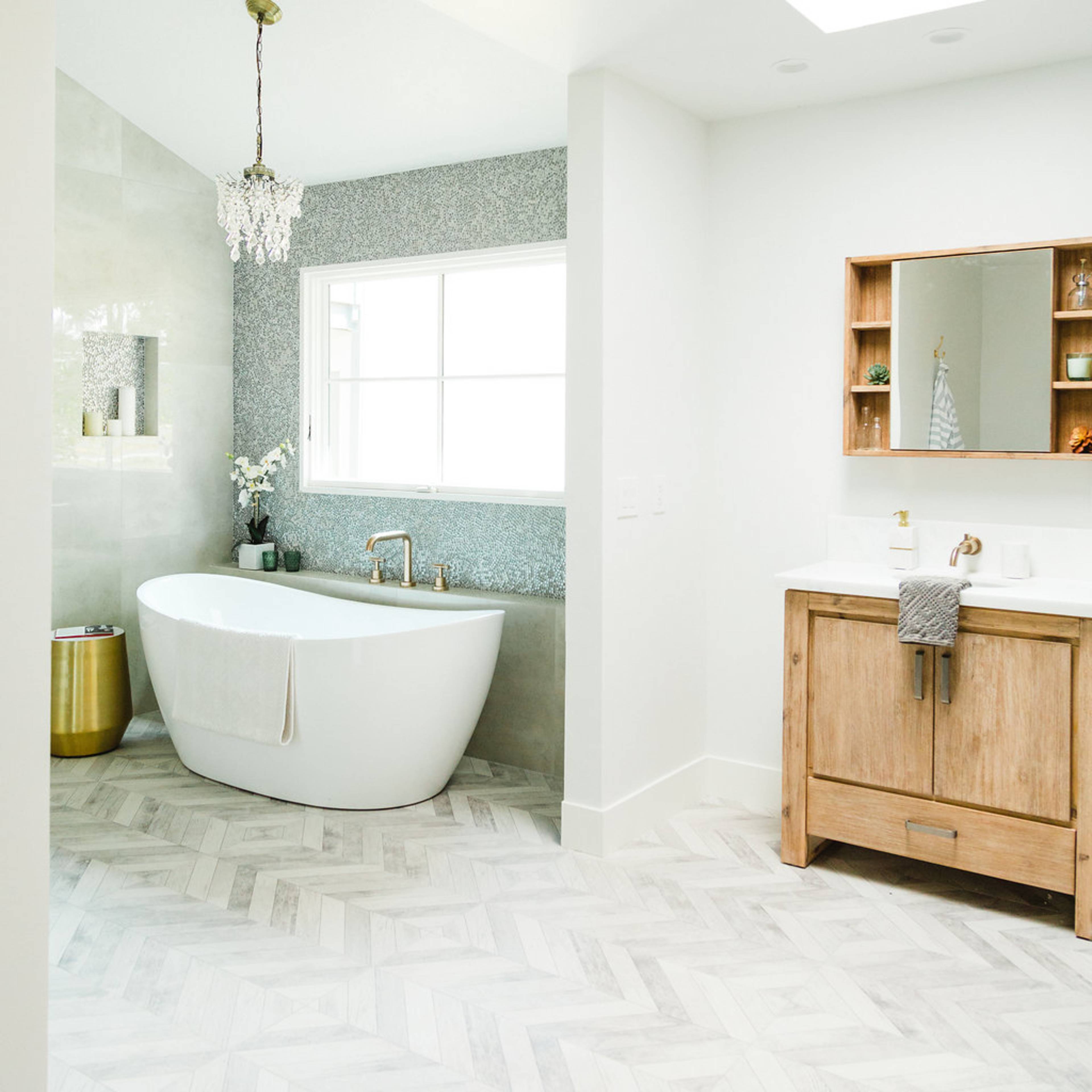 A modern bathroom featuring a freestanding bathtub, a wooden vanity, and a large window with a skylight.