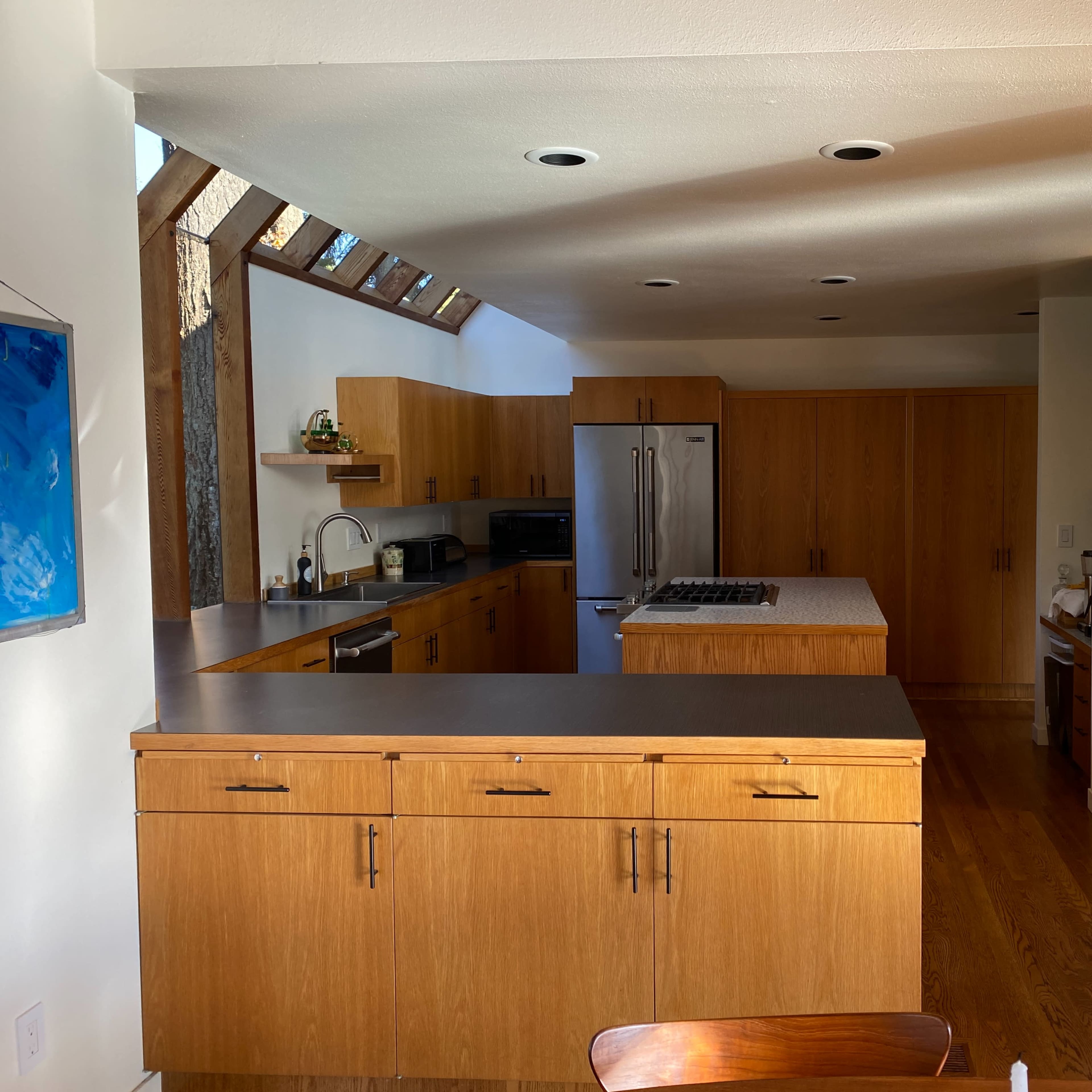 A modern kitchen with wooden cabinets, a central island, and stainless steel appliances.