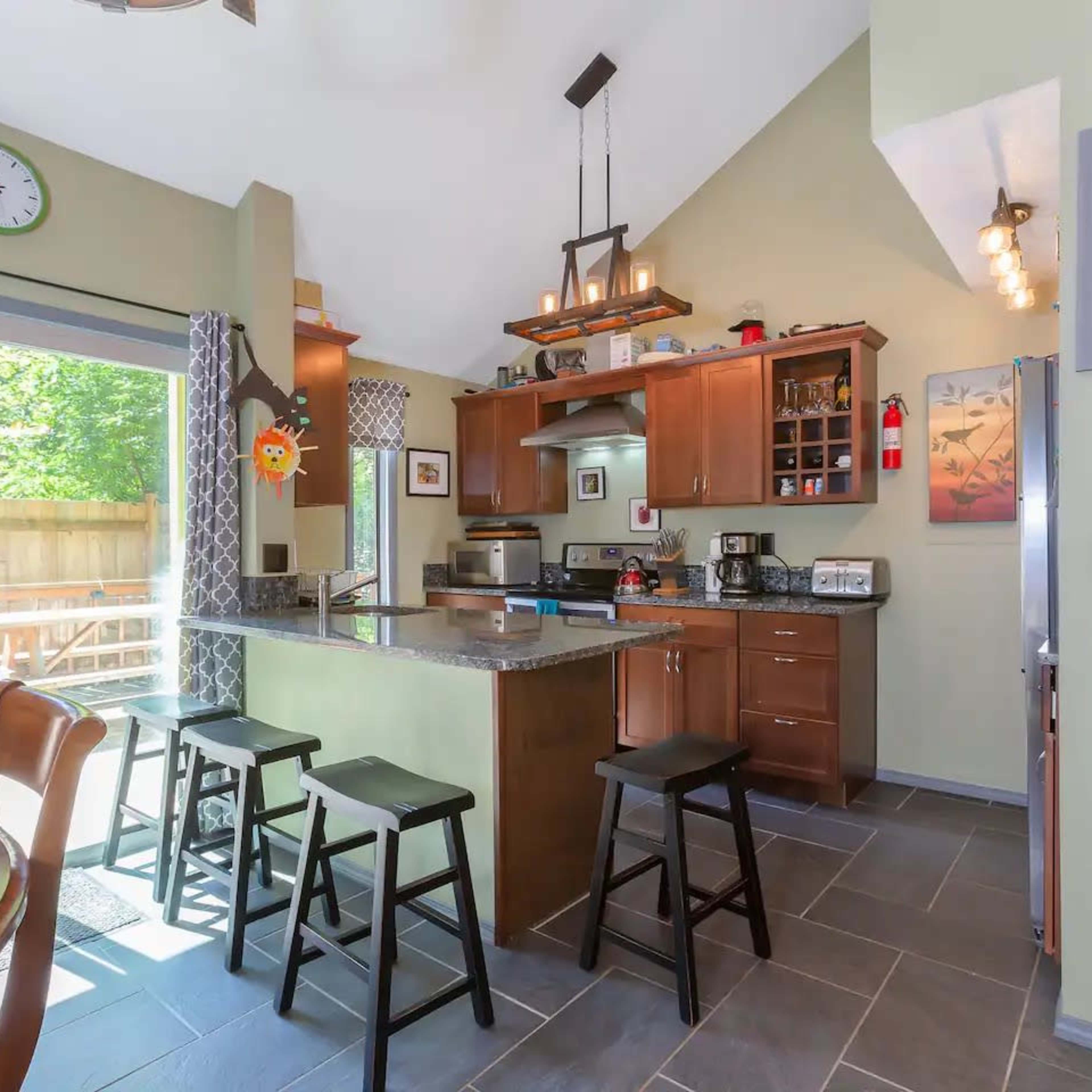 The kitchen features modern cabinetry, a central island with seating, and large windows that illuminate the space.