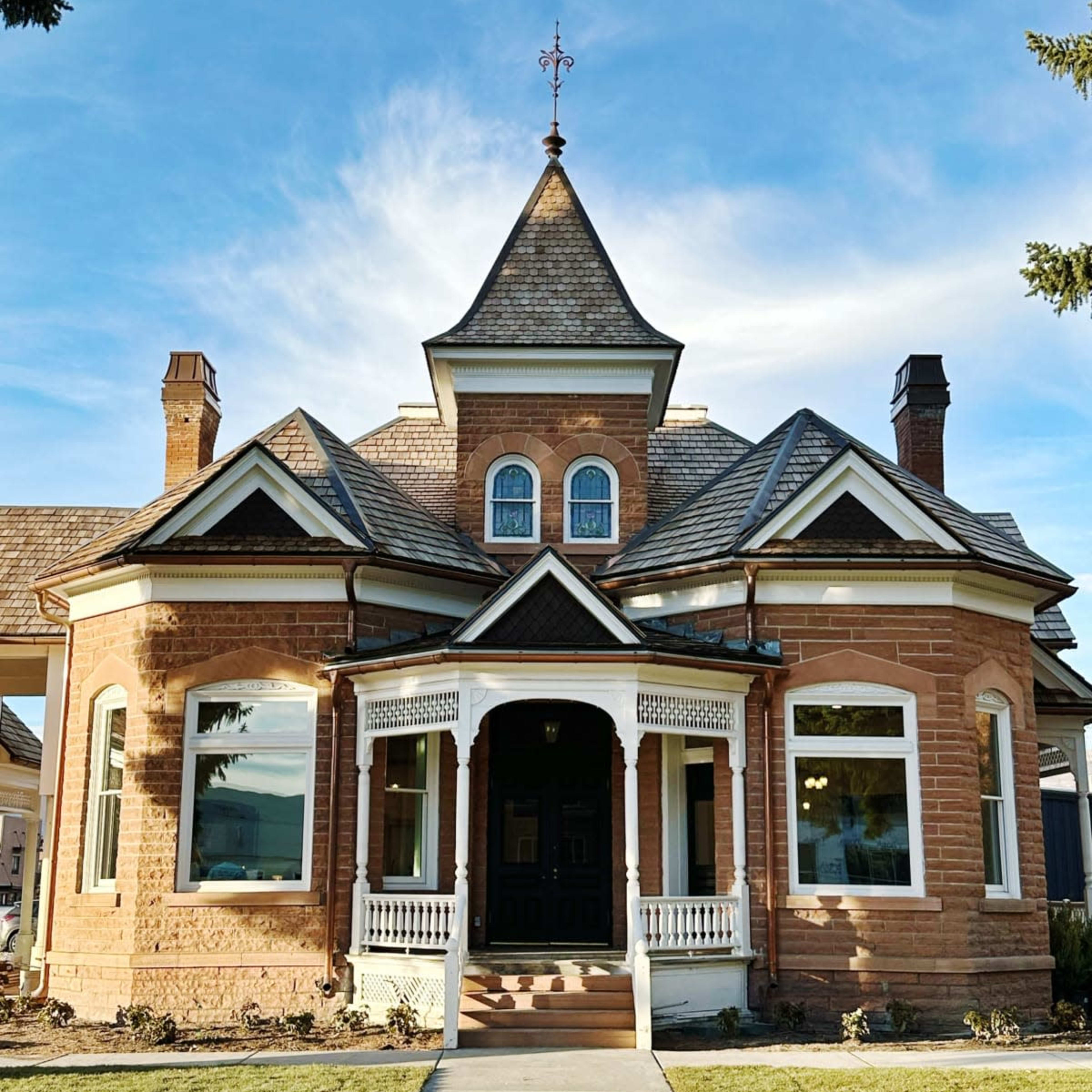 A large, historic brick house with a pointed roof, decorative trim, and multiple windows.