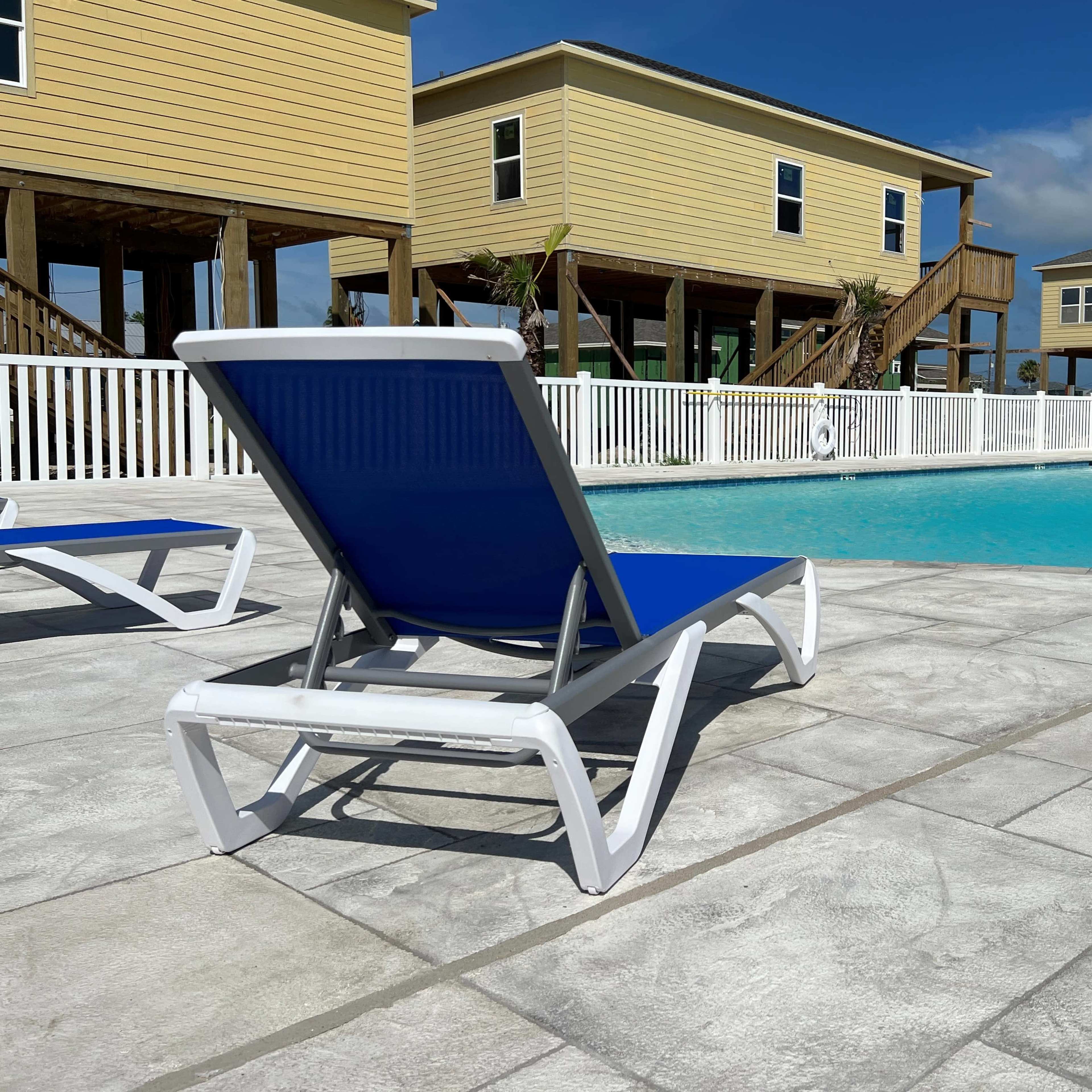A poolside area features lounge chairs facing a clear blue pool surrounded by elevated wooden houses.