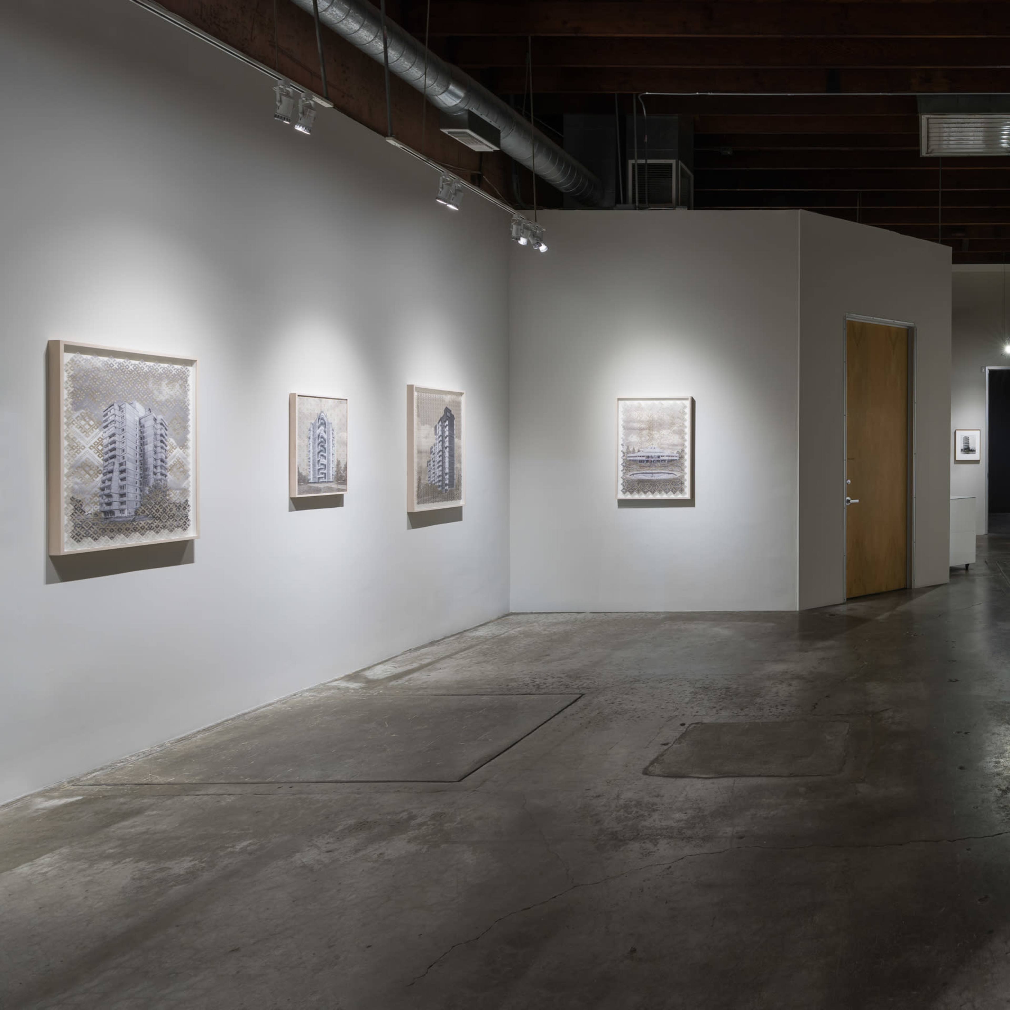 A modern art gallery with framed artworks displayed along the walls and a doorway leading to another area.