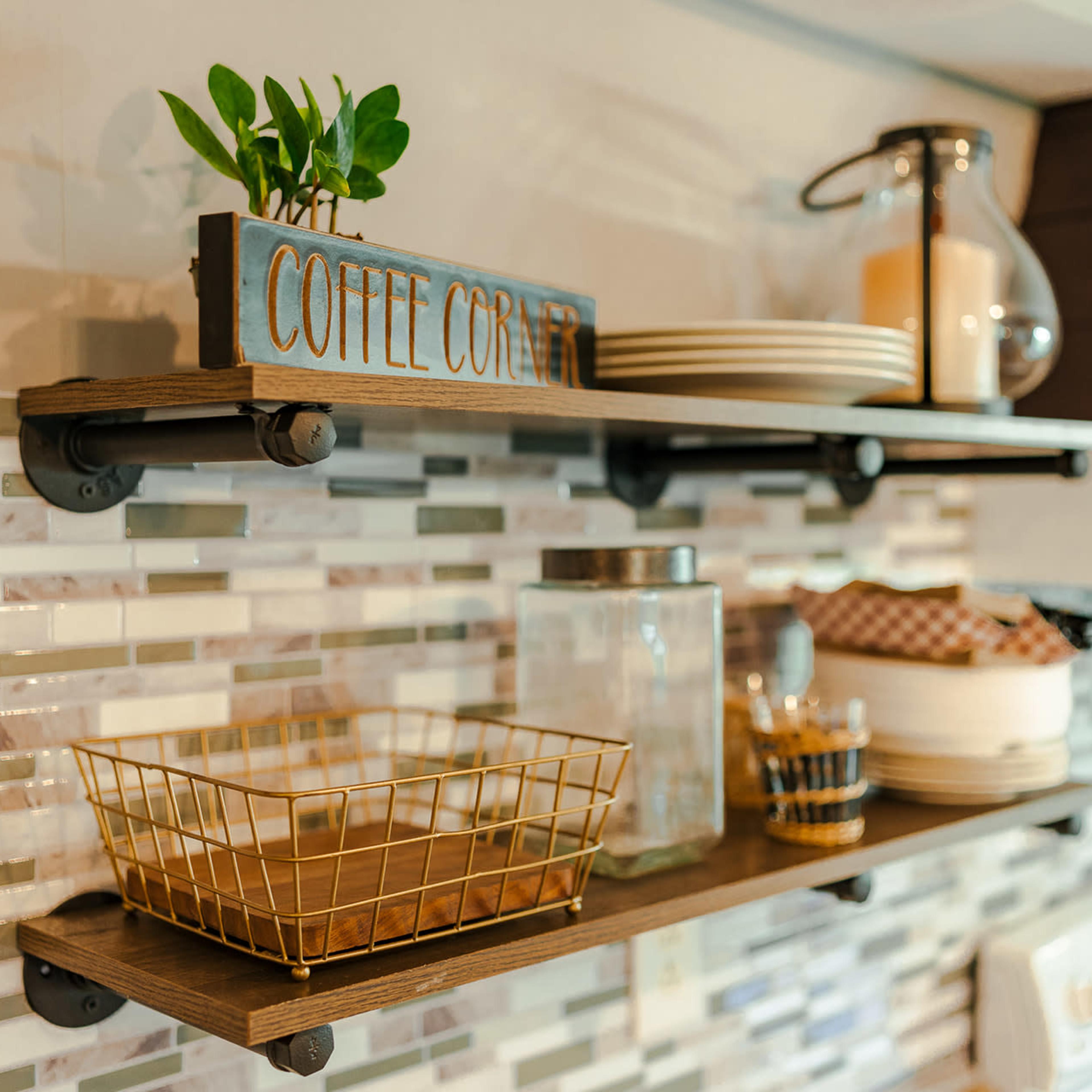 Wooden shelves in a kitchen with decorative items, including a coffee-themed sign, a plant, and various containers arranged neatly.