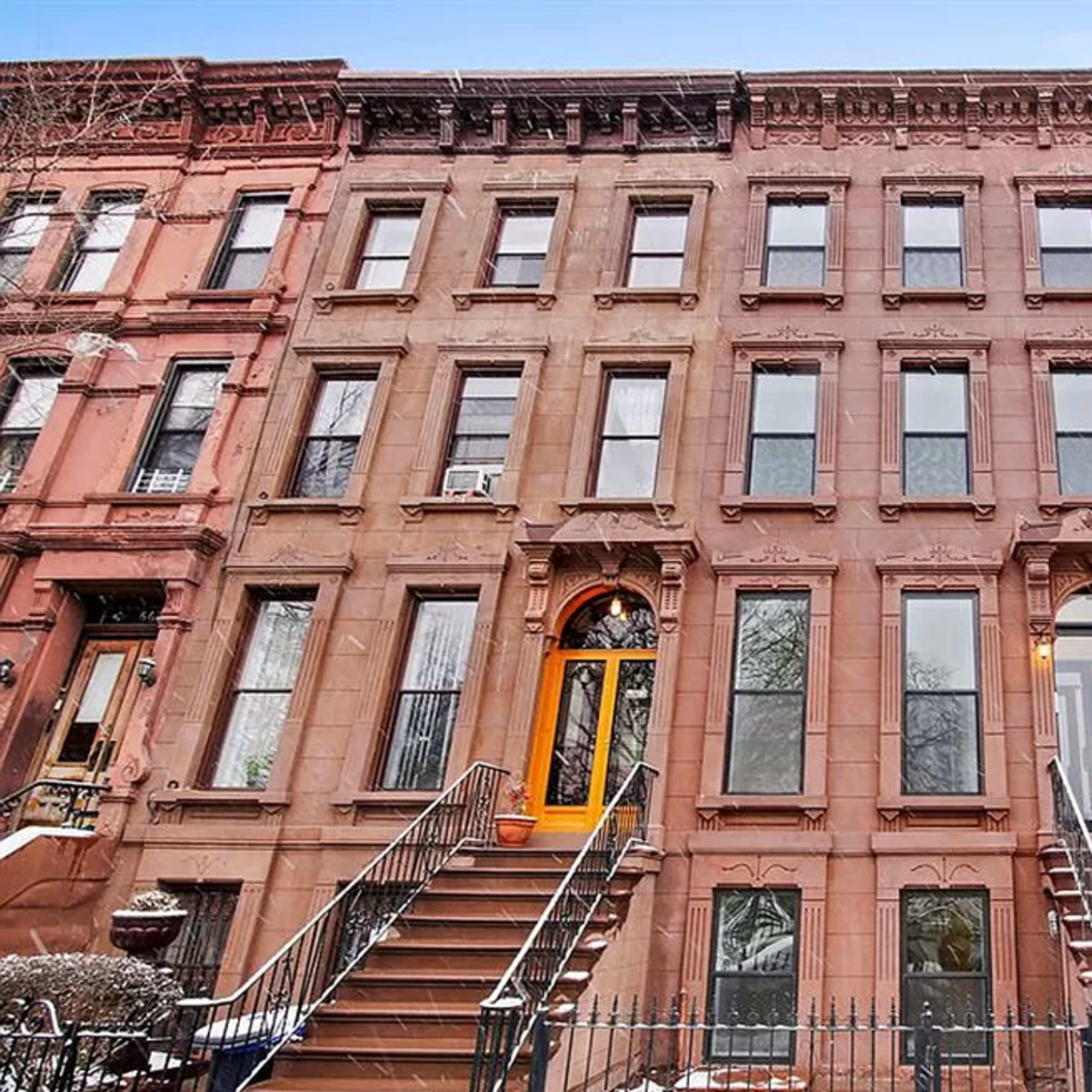 A row of three multi-story residential buildings with distinct architectural styles, including brownstone facades and a modern exterior, set against a clear sky.
