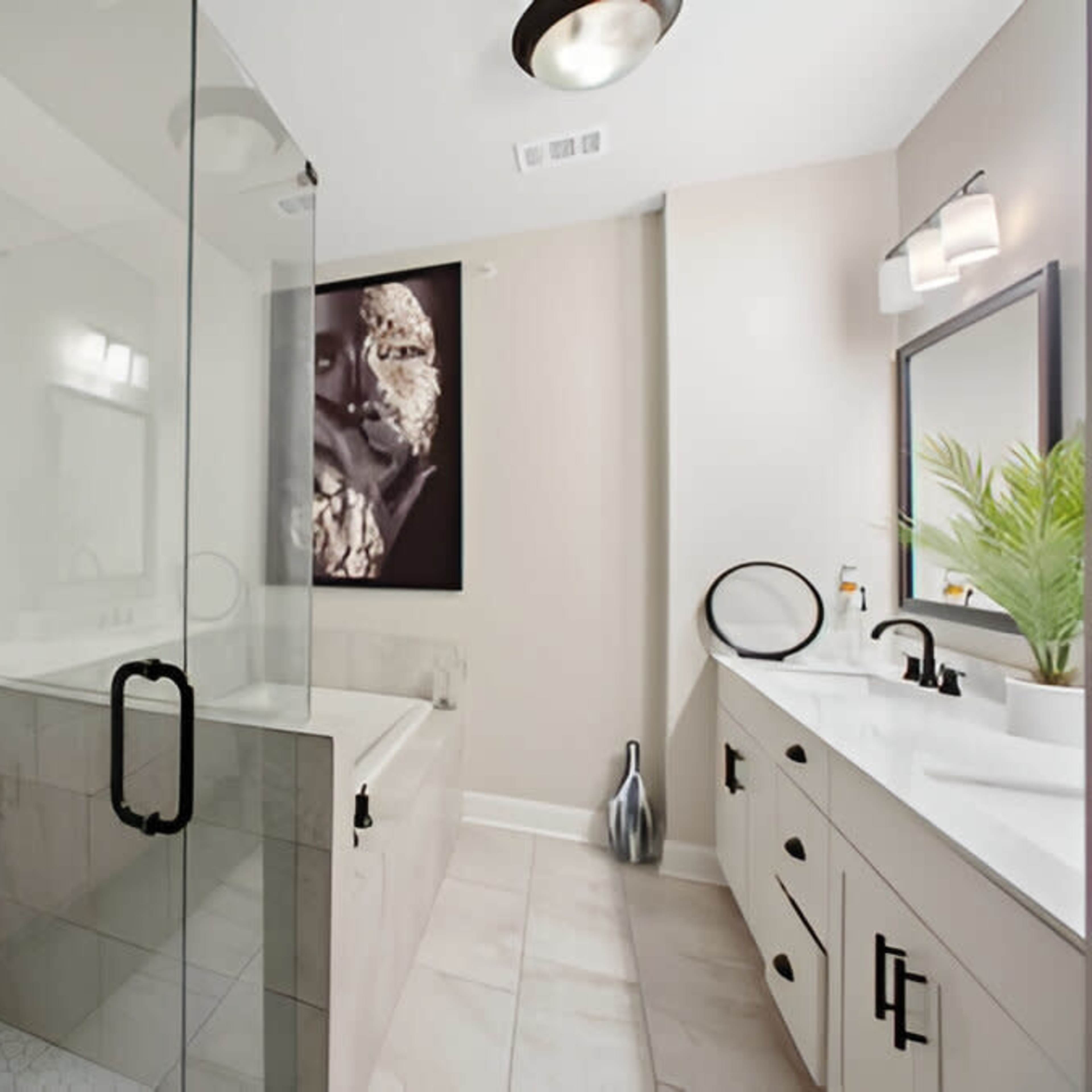A modern bathroom featuring a glass shower enclosure, a freestanding bathtub, and a double vanity with a large mirror.