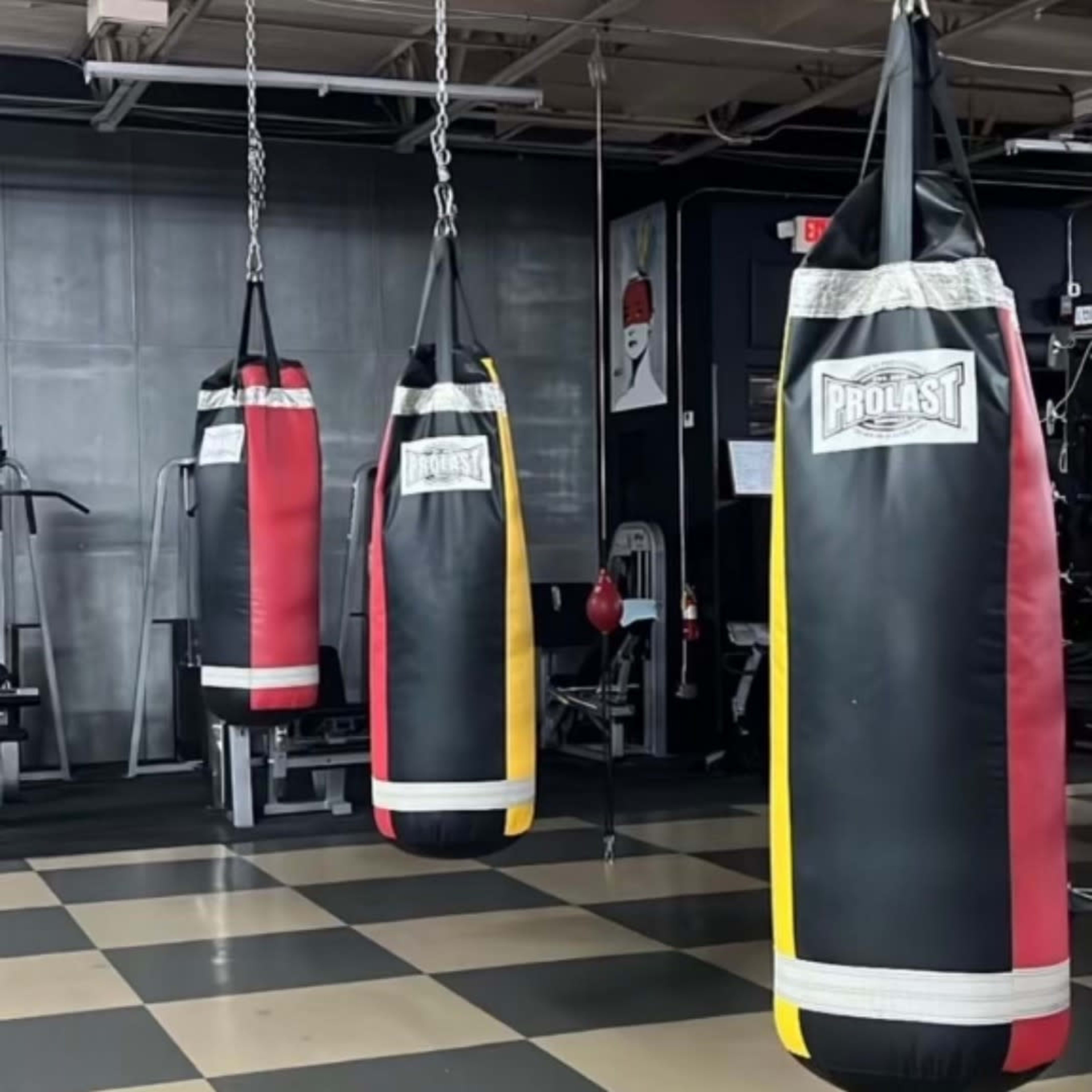 Three hanging boxing bags in a gym setting are arranged in a row.