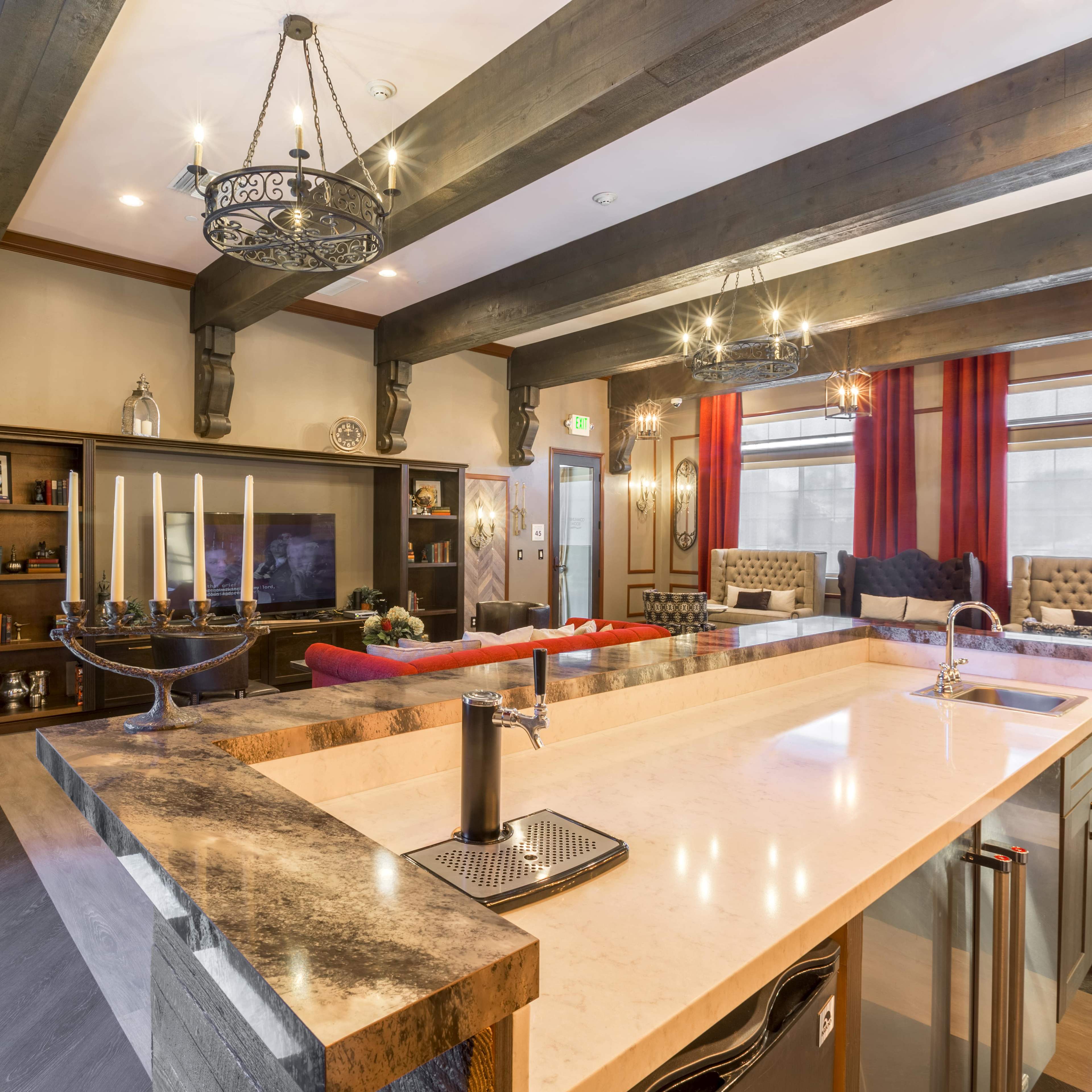 A modern kitchen and living area with a large island, leather sofas, and decorative lighting fixtures.
