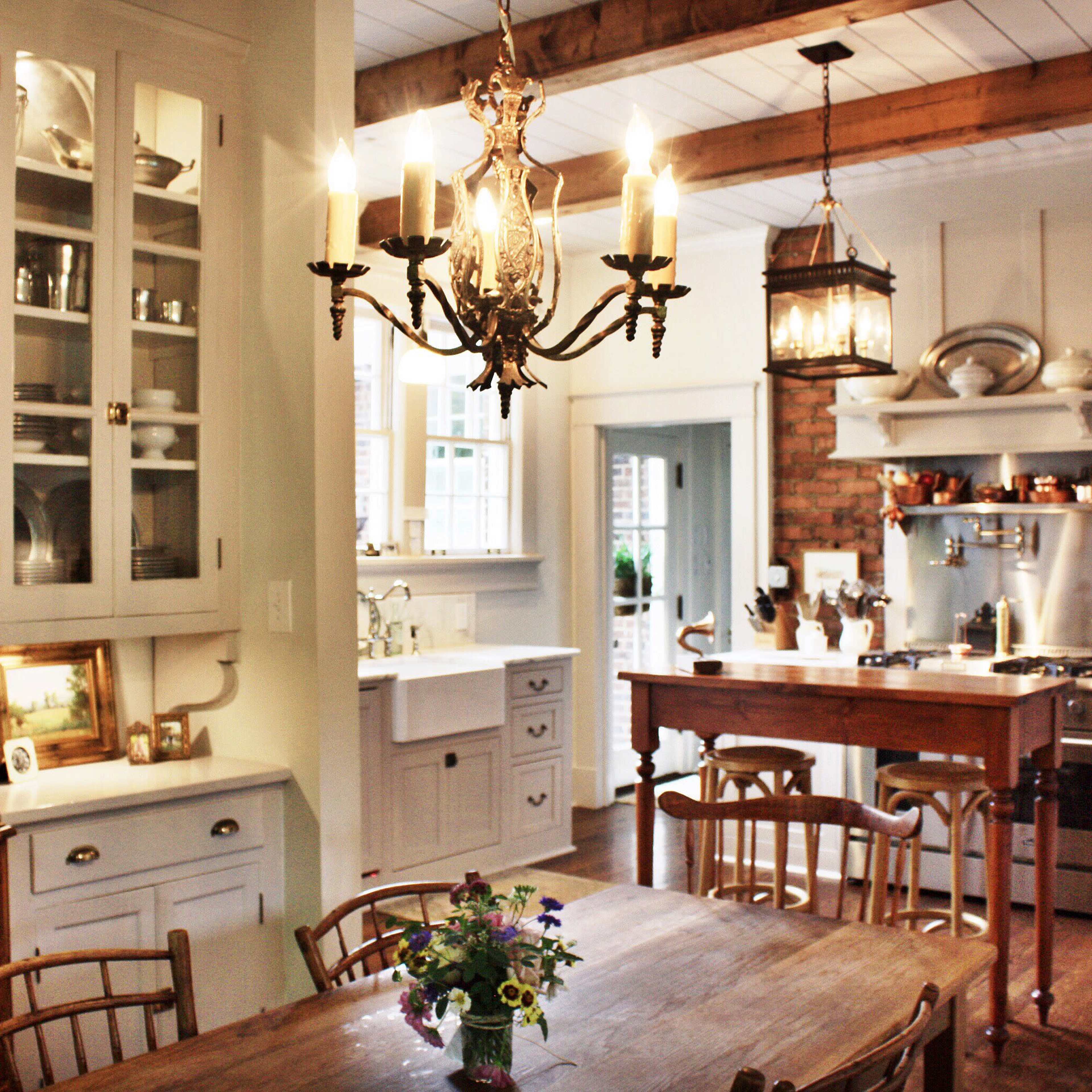 A well-lit kitchen and dining area featuring a wooden table with chairs, a chandelier, and a mix of modern and traditional decor.