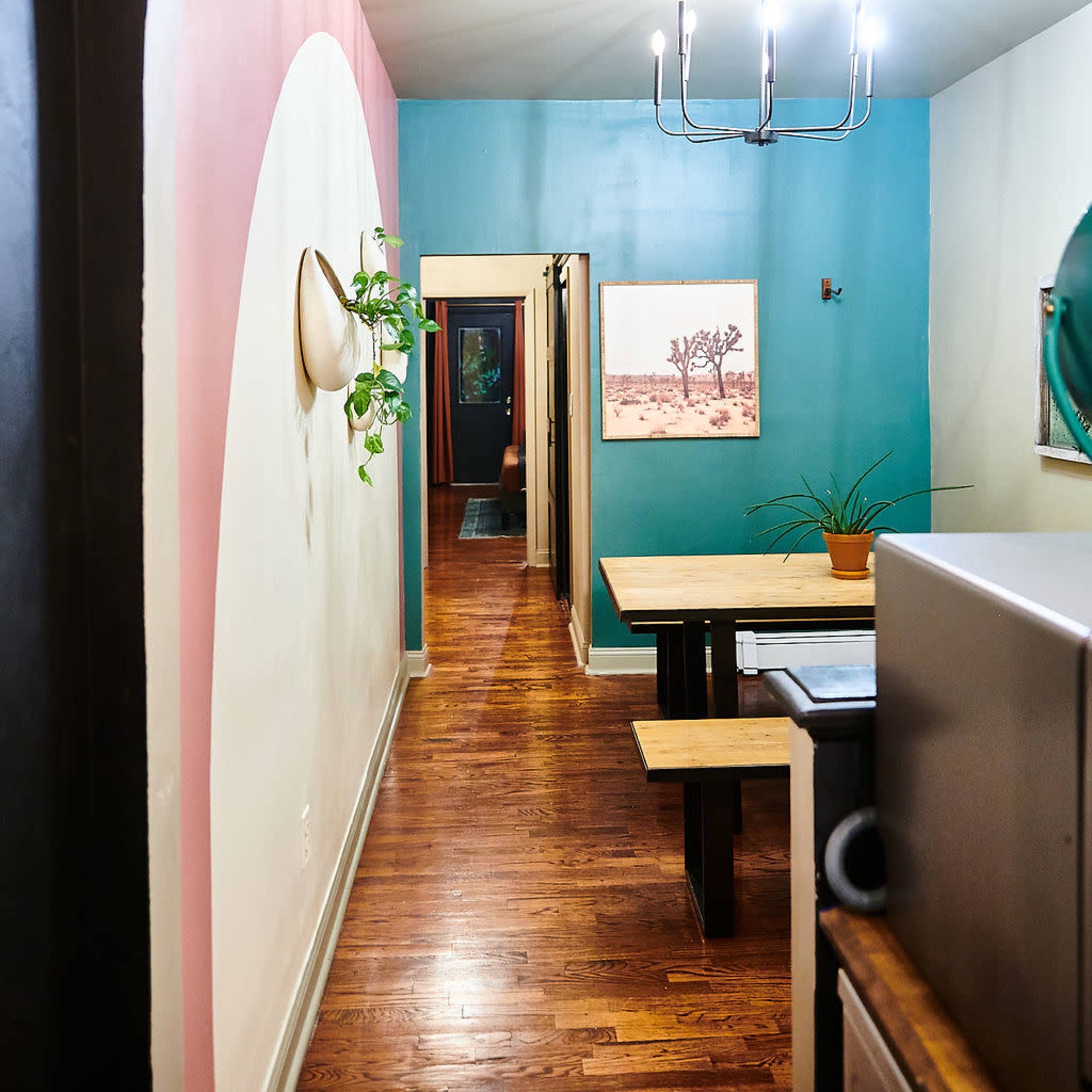A brightly lit hallway with a colorful wall design, leading to a dining area and a series of doors.