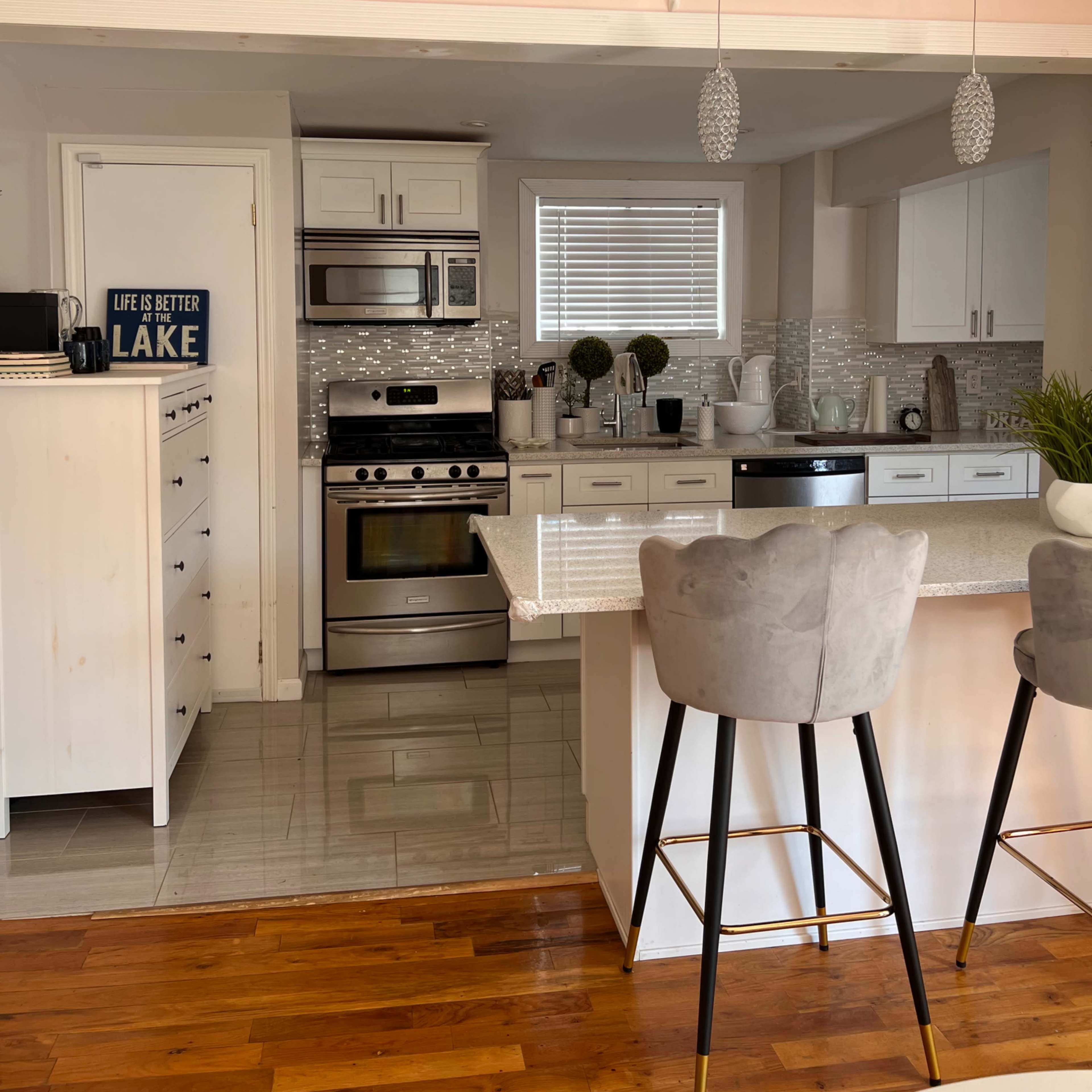A modern kitchen with white cabinetry, stainless steel appliances, and a central island with bar stools.