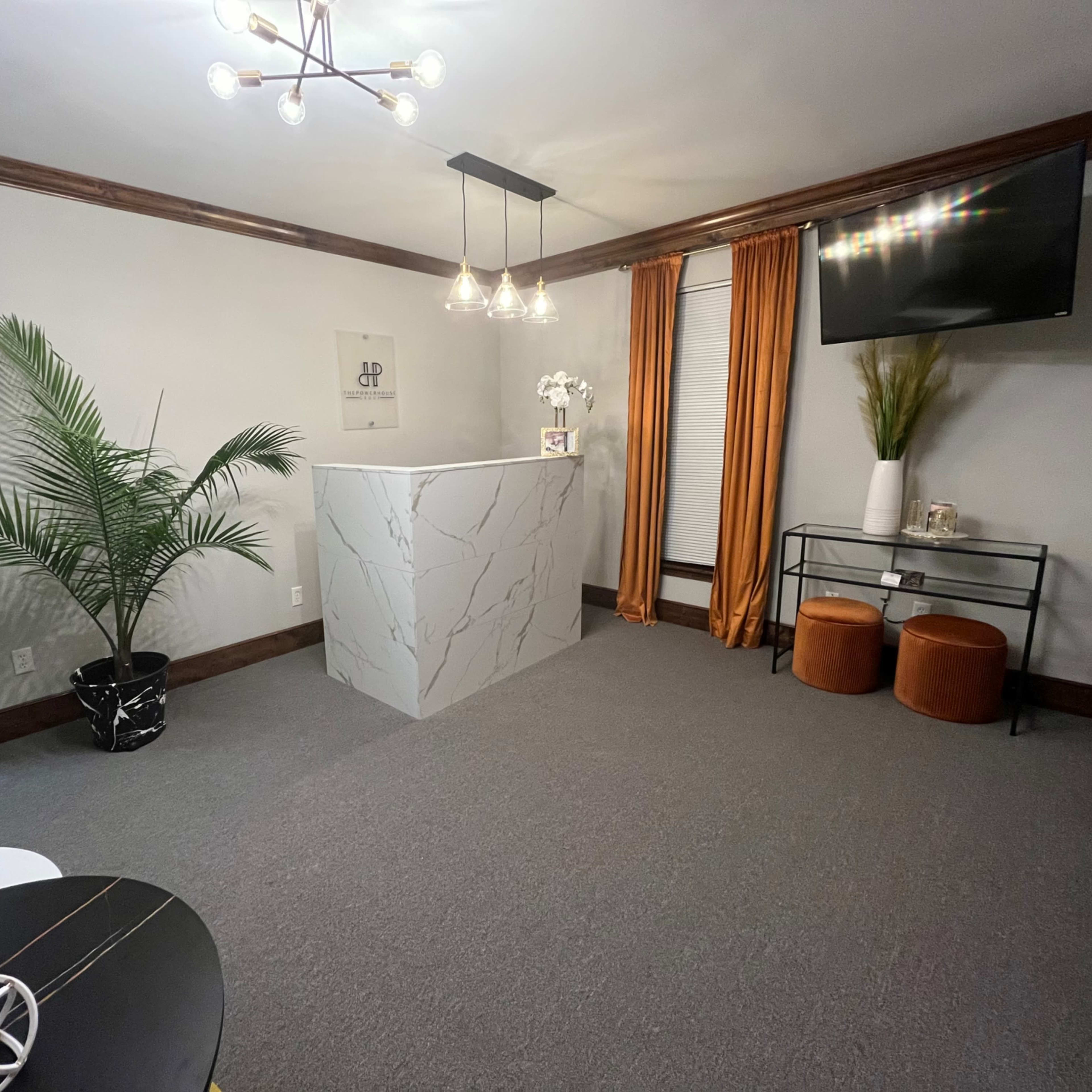 A modern reception area featuring a marble reception desk, textured curtains, and a plant in a decorative pot.