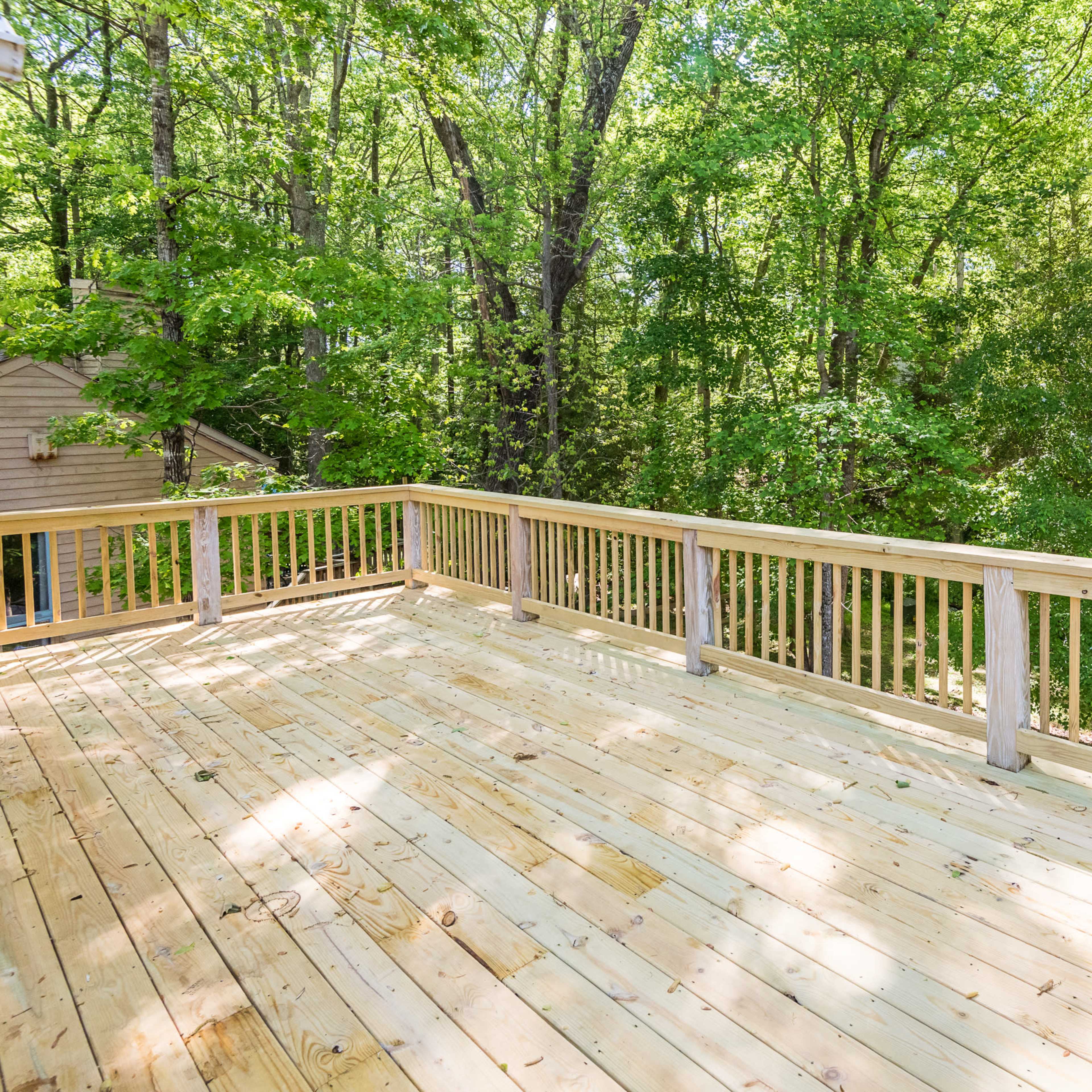A wooden deck surrounded by dense trees in a forested area.