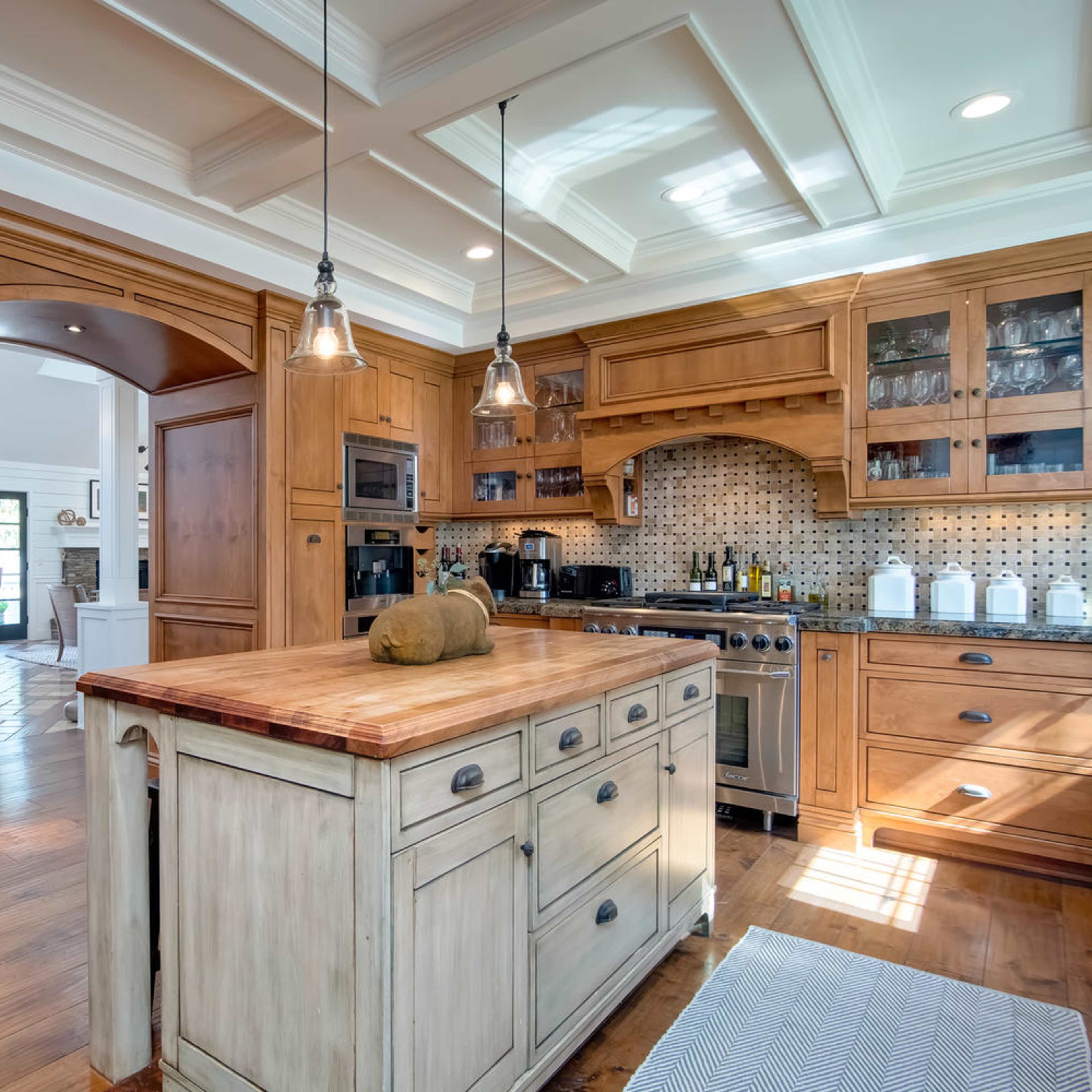 A spacious kitchen with wooden cabinetry, a central island with a butcher block top, and modern appliances.