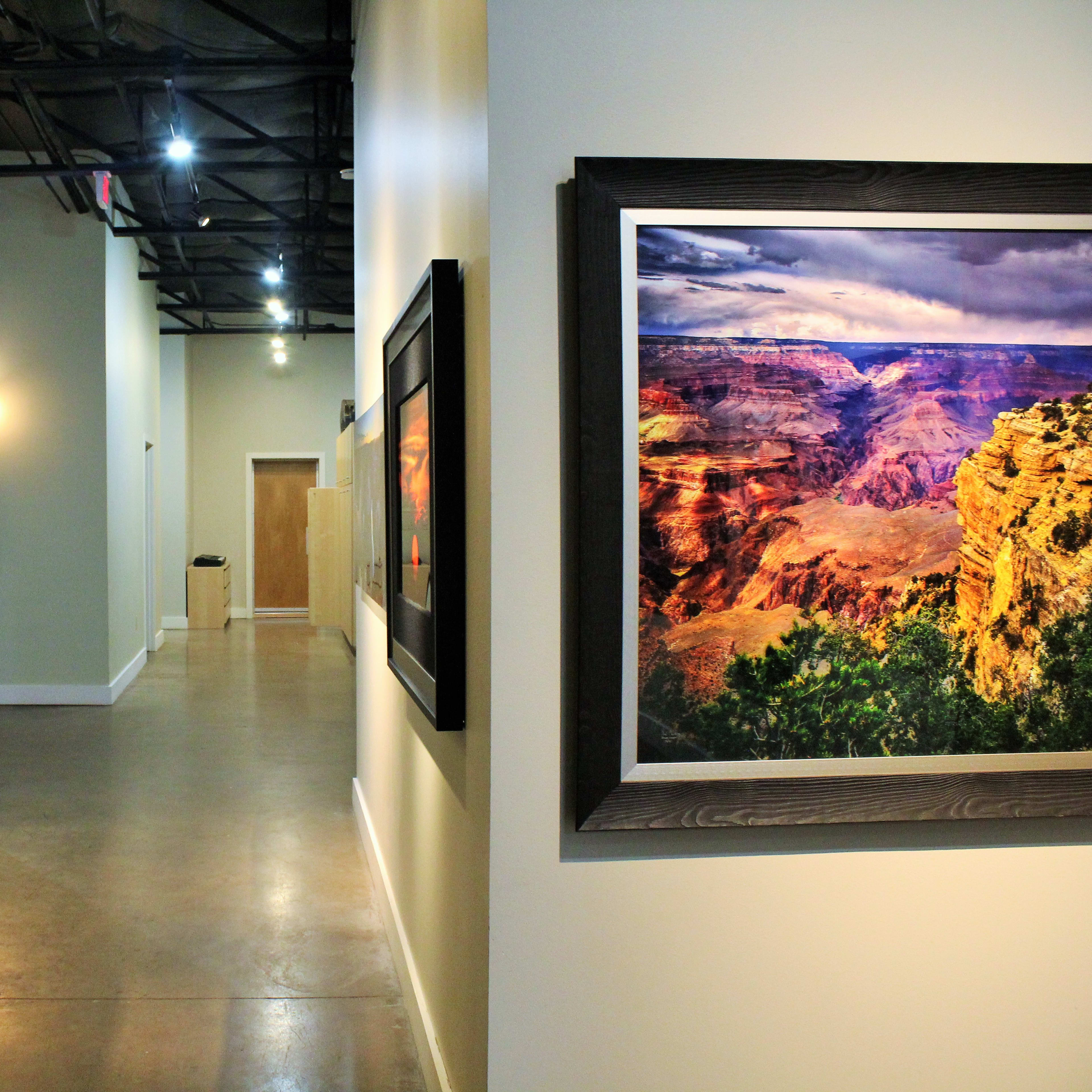 A long, narrow hallway is lined with artwork on the walls, leading to a door at the end.
