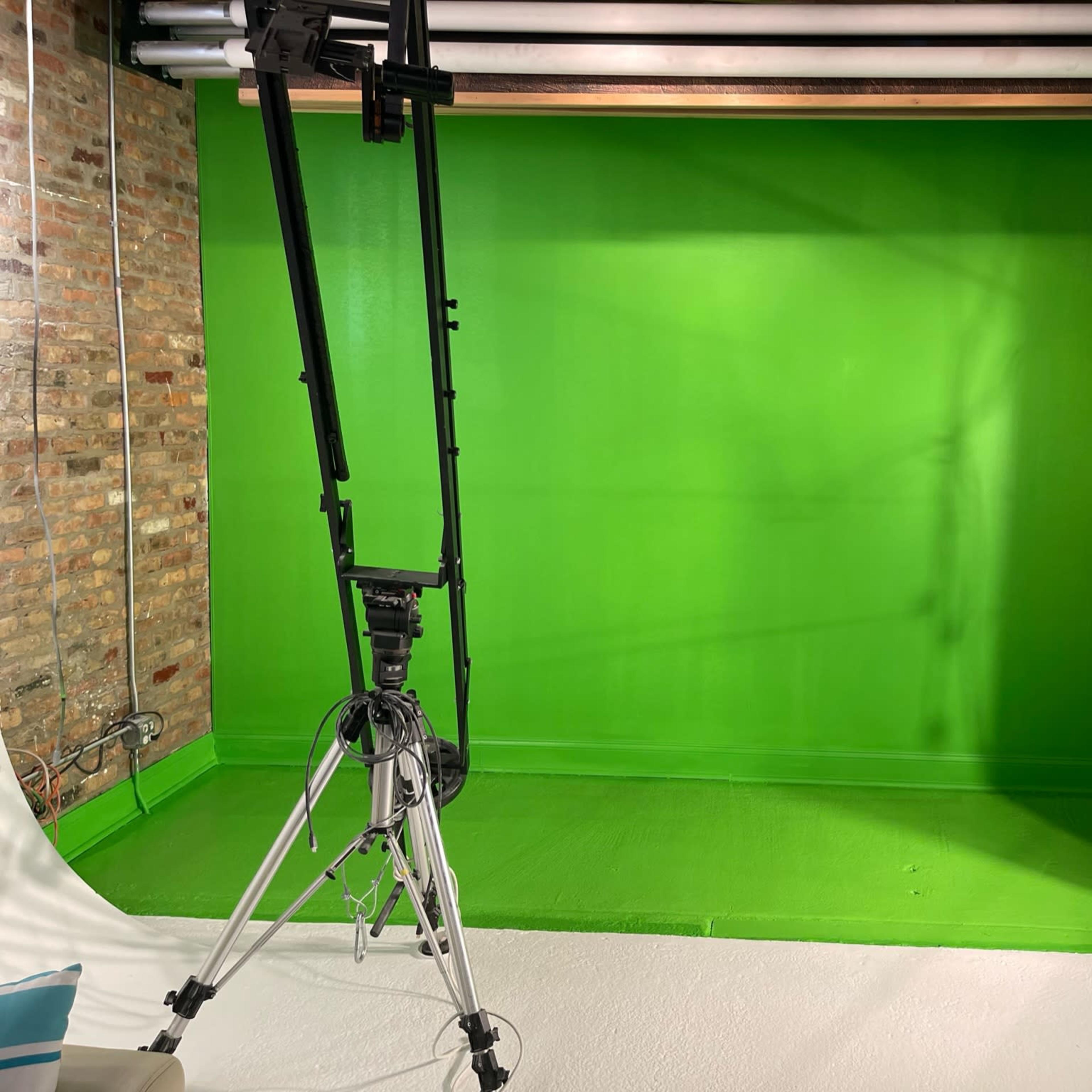 A green screen backdrop set up in a studio with lighting equipment and exposed brick walls.
