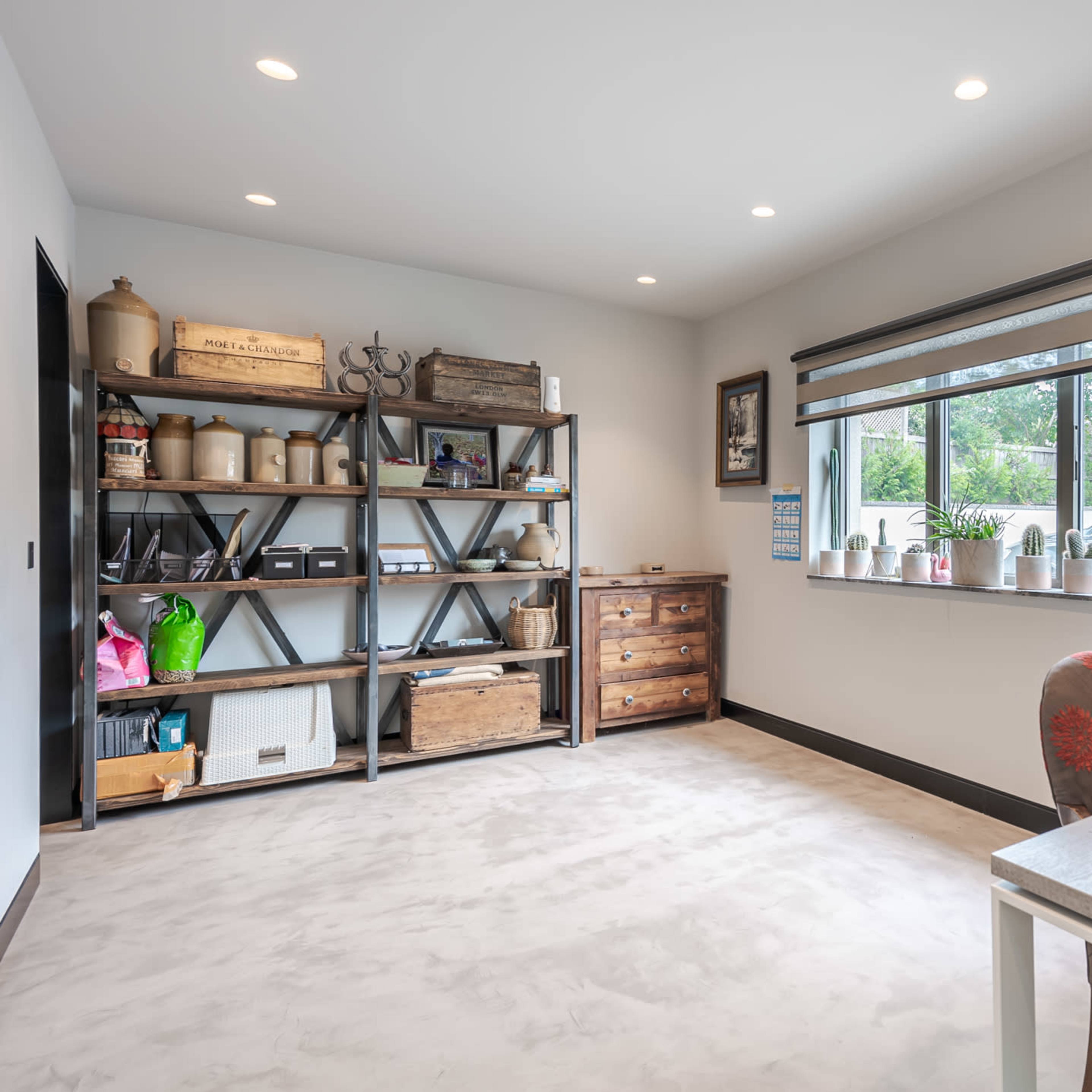 A well-lit room features a wooden desk and shelving unit filled with various storage boxes and decorative items.