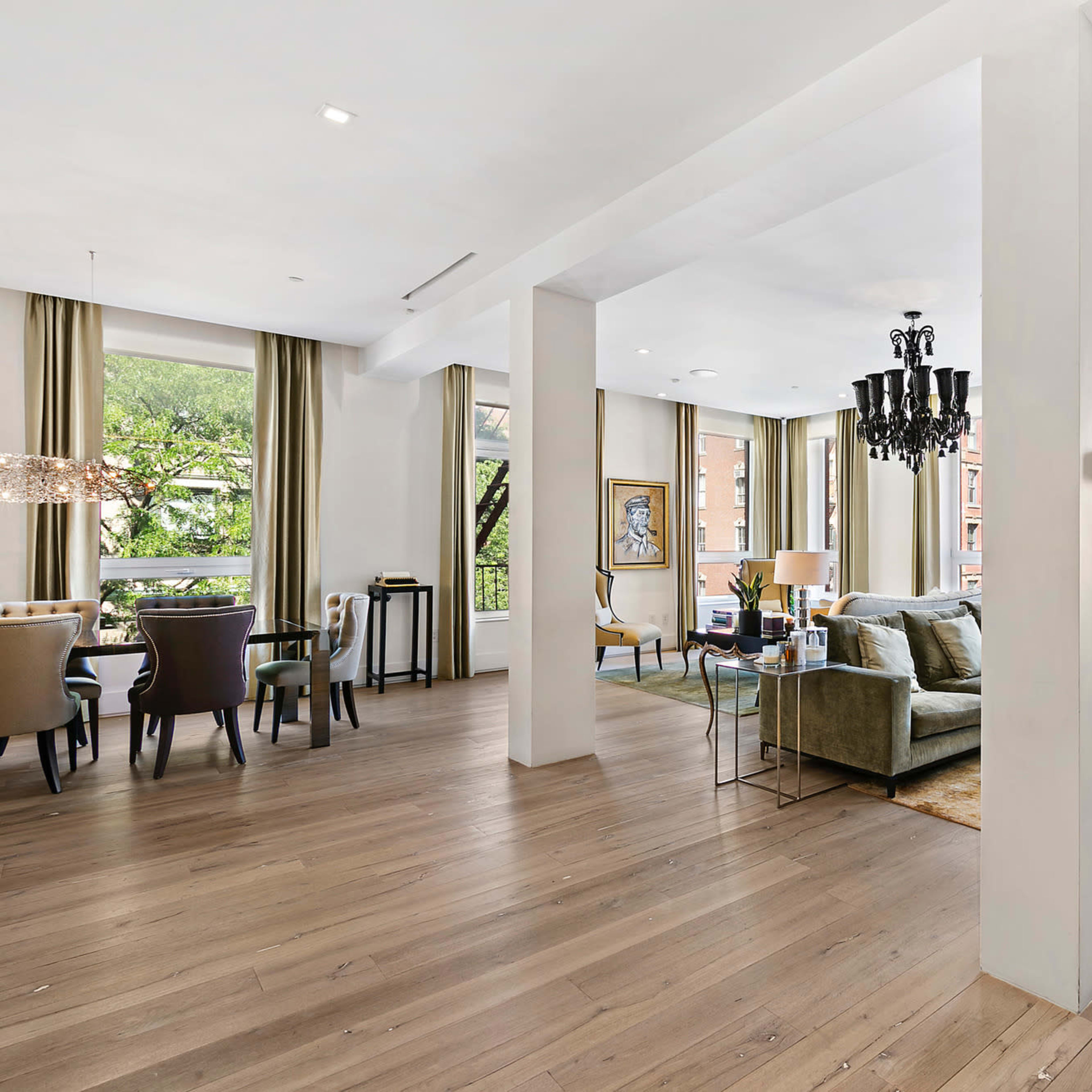 A spacious, bright living area featuring a seating arrangement, dining area, and large windows that allow natural light to fill the room.