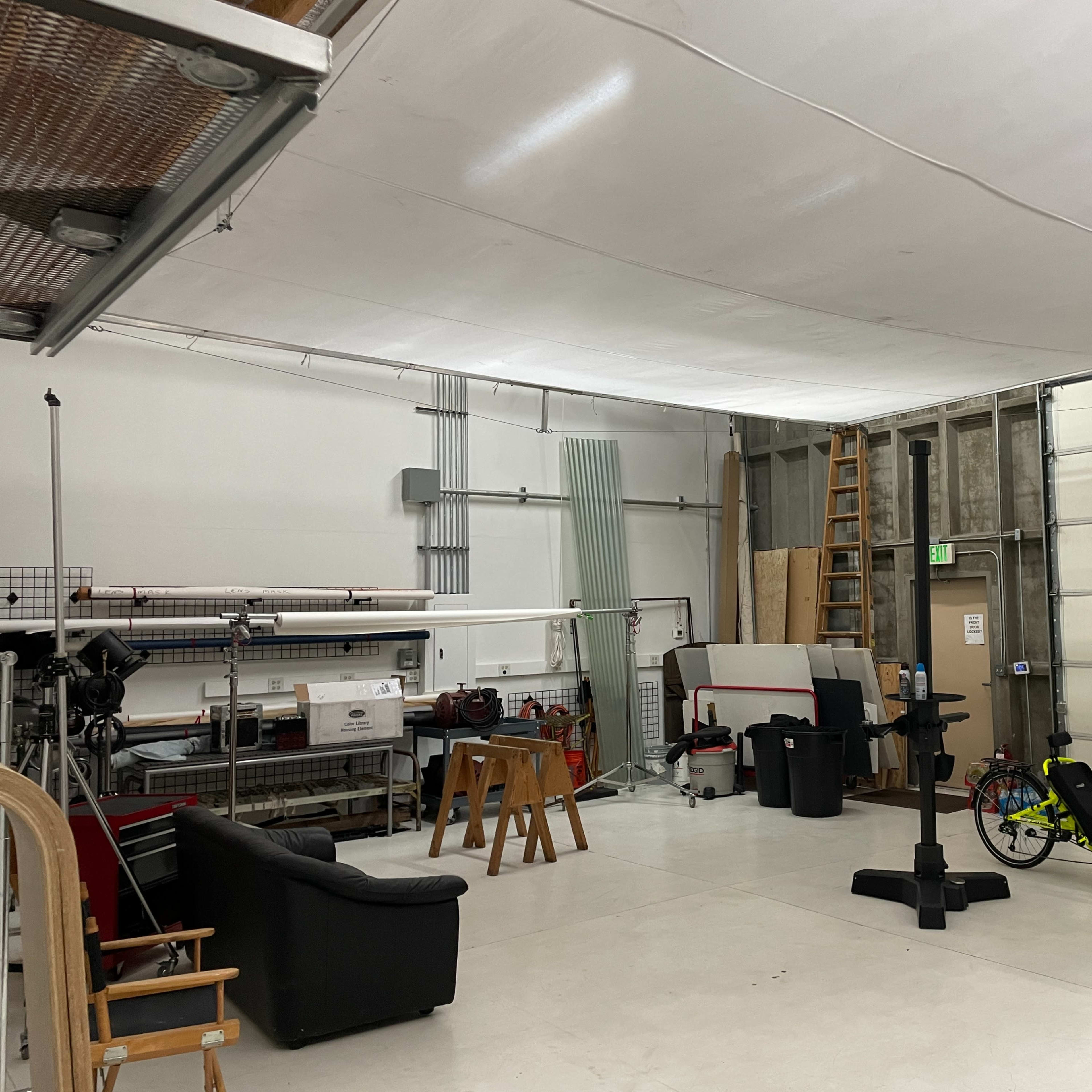 A spacious garage or workshop with various equipment, furniture, and bicycles arranged inside.