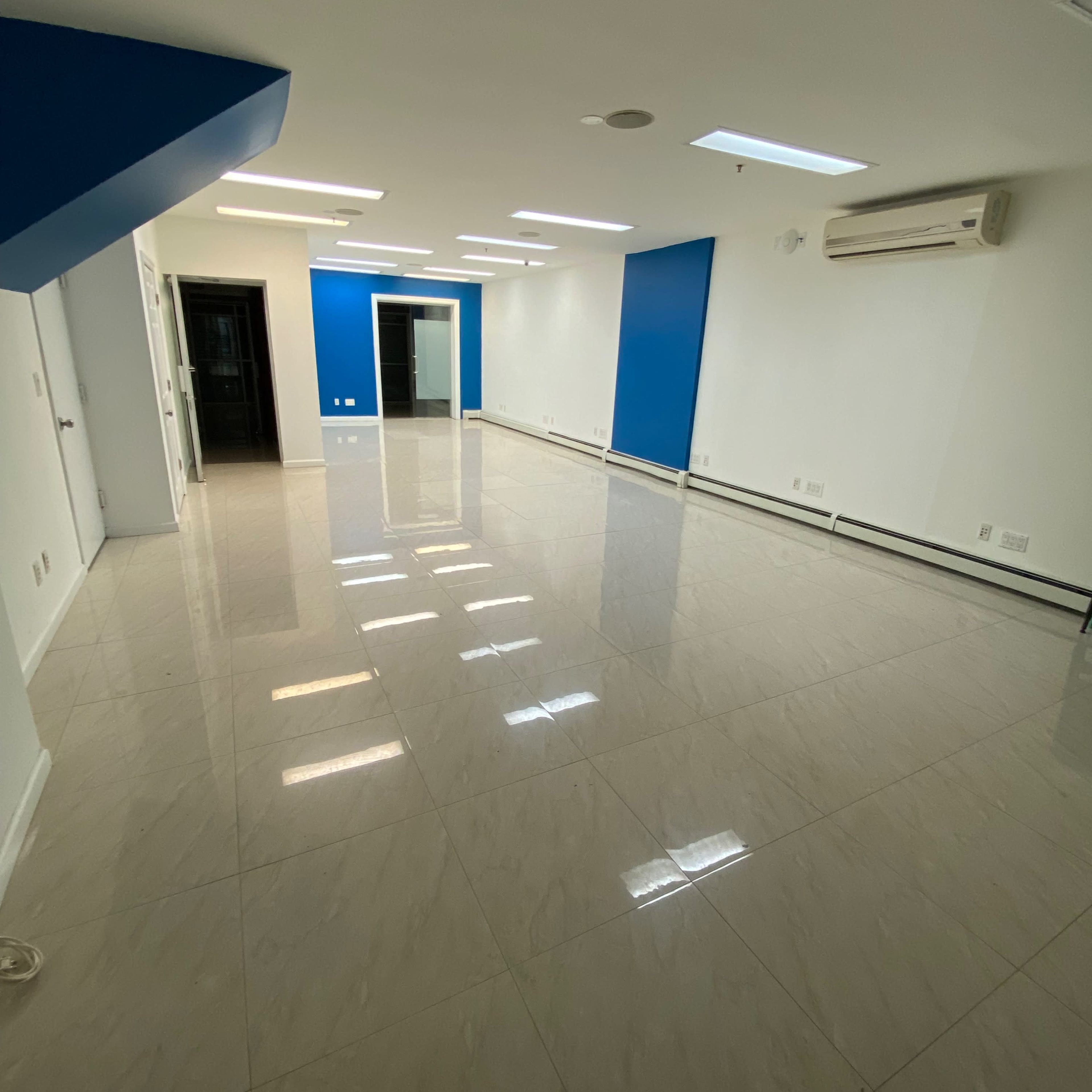 A spacious, empty room with glossy tiled flooring and blue accent walls.