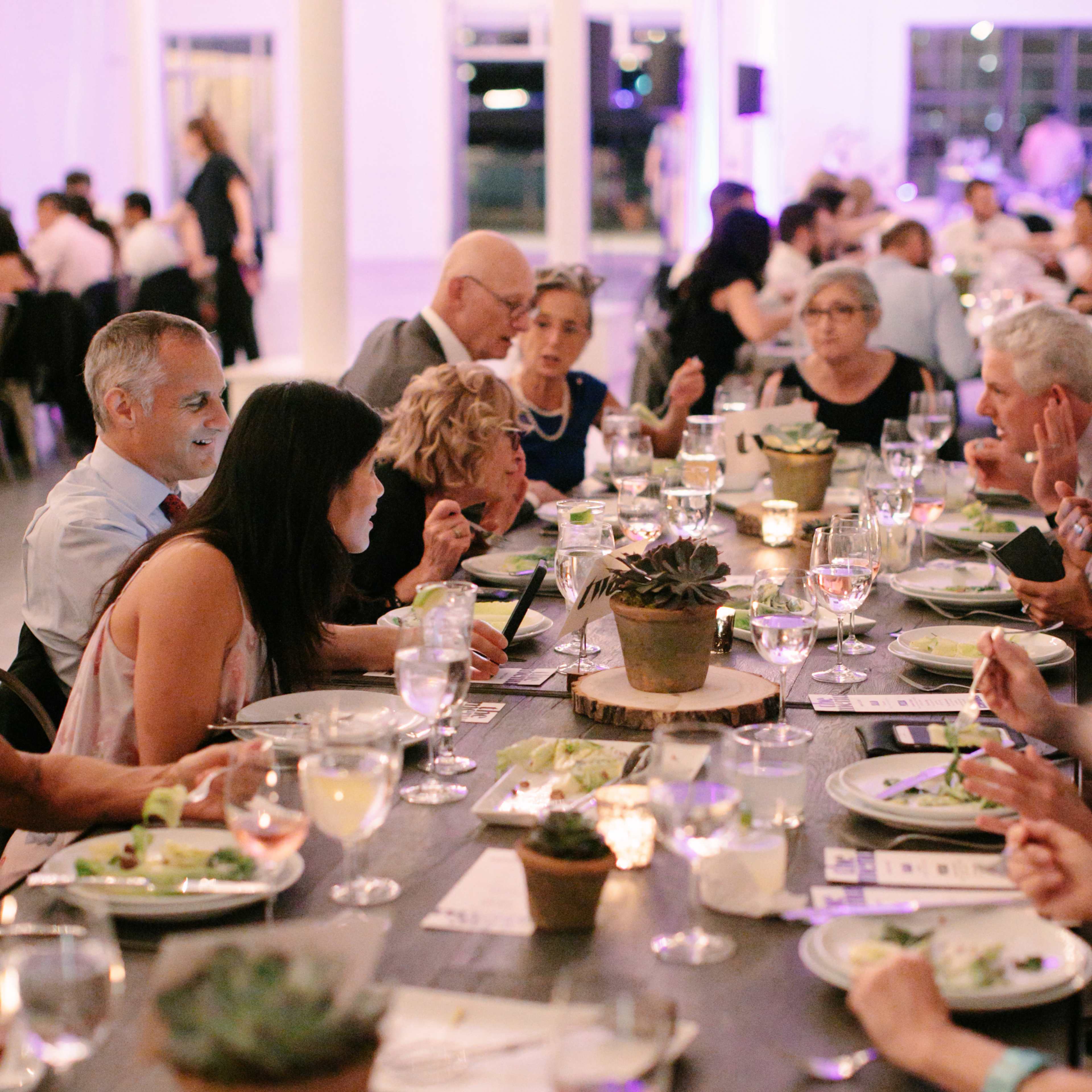 A long dining table filled with people enjoying a meal at an elegantly decorated venue.