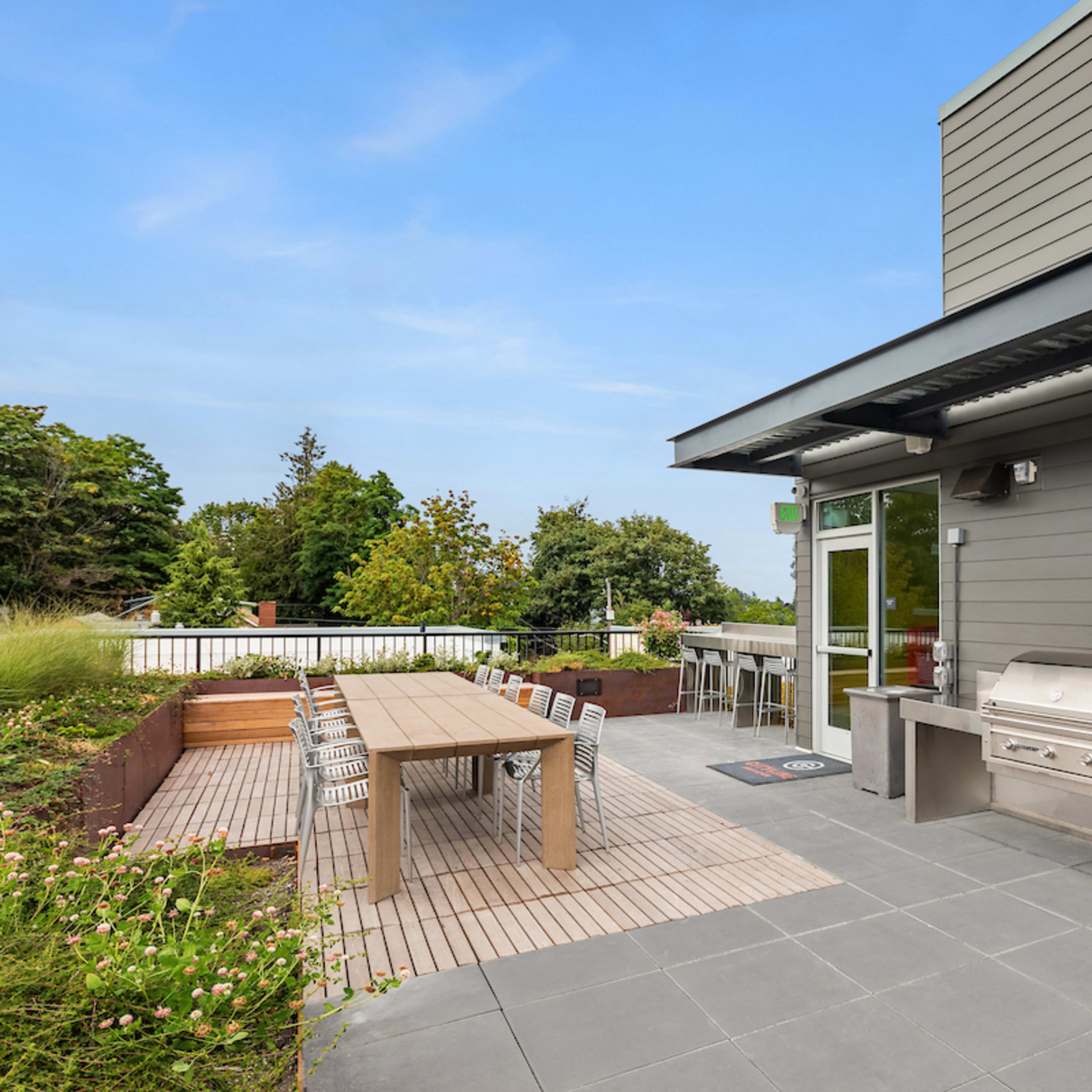 A rooftop terrace featuring seating areas, lounge chairs, and landscaping with various plants and flowers.
