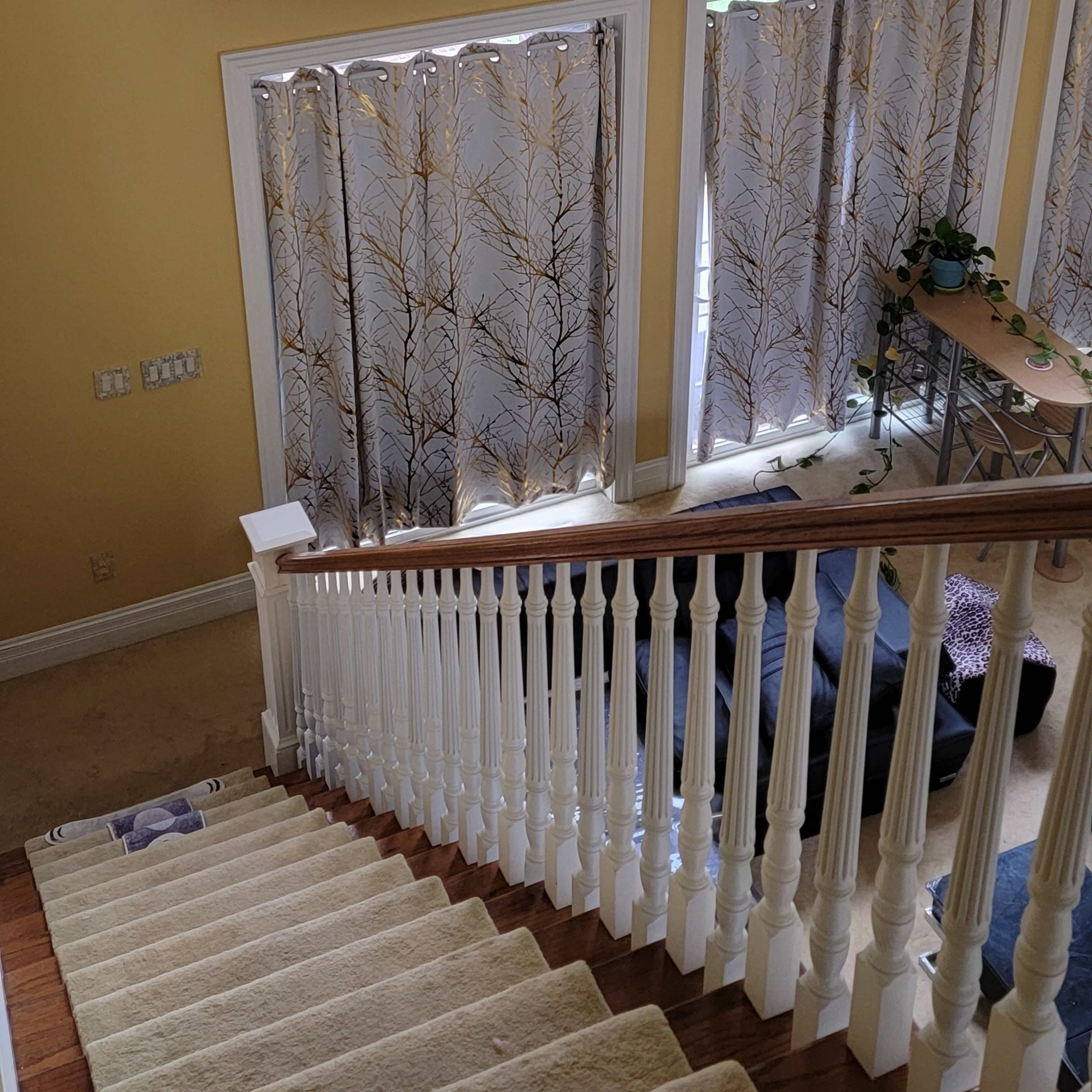 A staircase leading down to a living space, with large arched windows allowing natural light to illuminate the area.