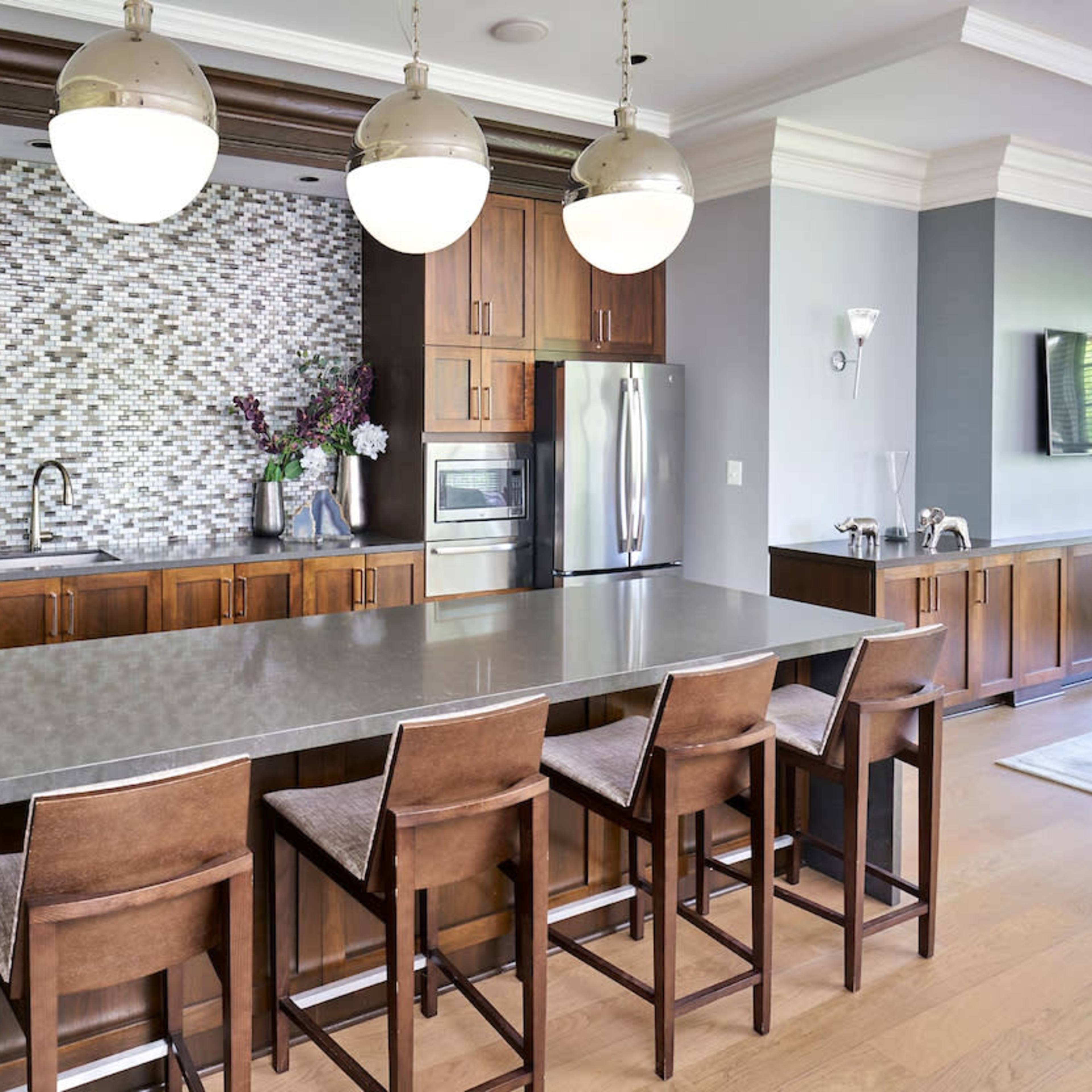 The kitchen features dark wooden cabinetry, a large gray island with bar stools, and a tiled backsplash behind the sink.
