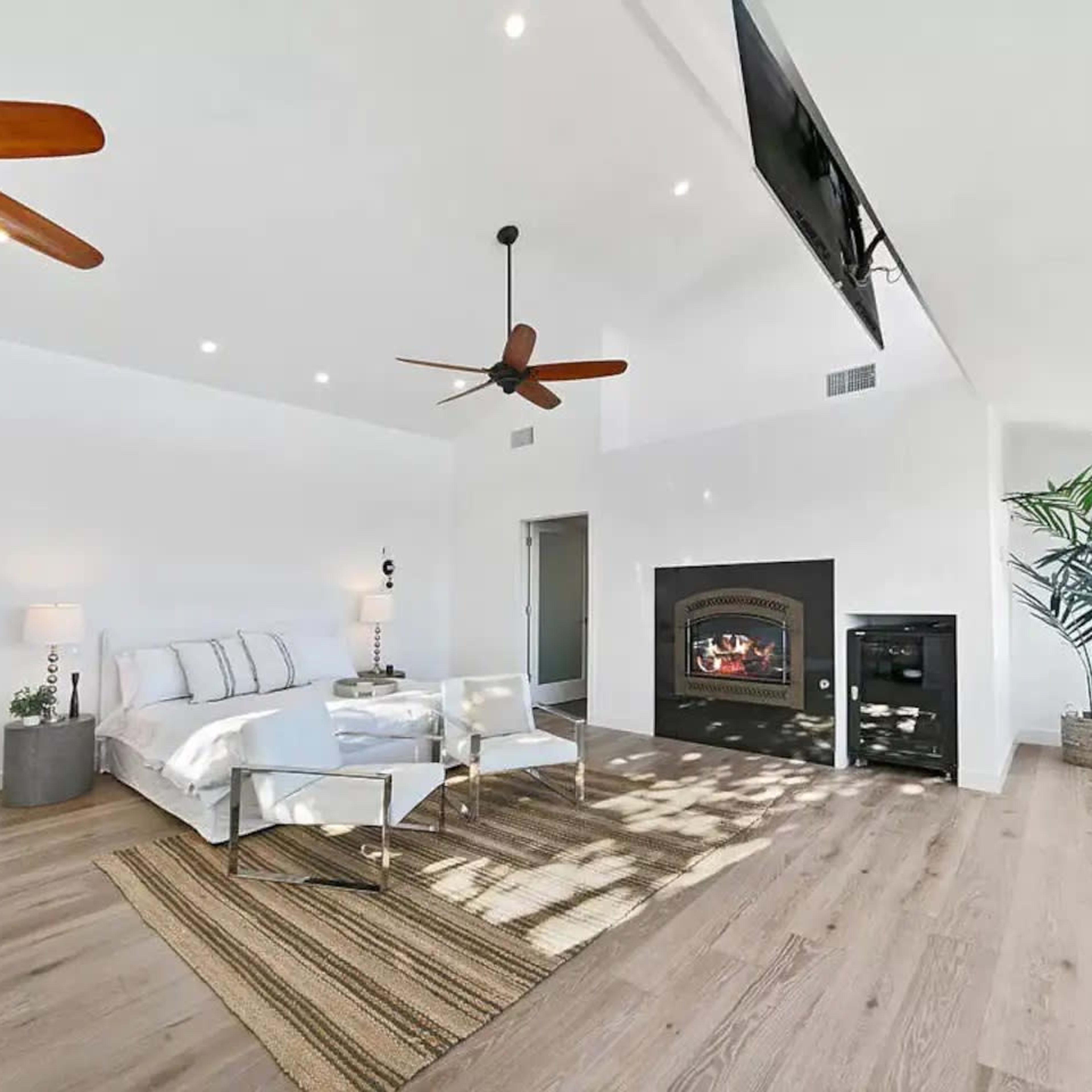The room features a modern bedroom with a large bed, a fireplace, and large windows that allow natural light to fill the space.