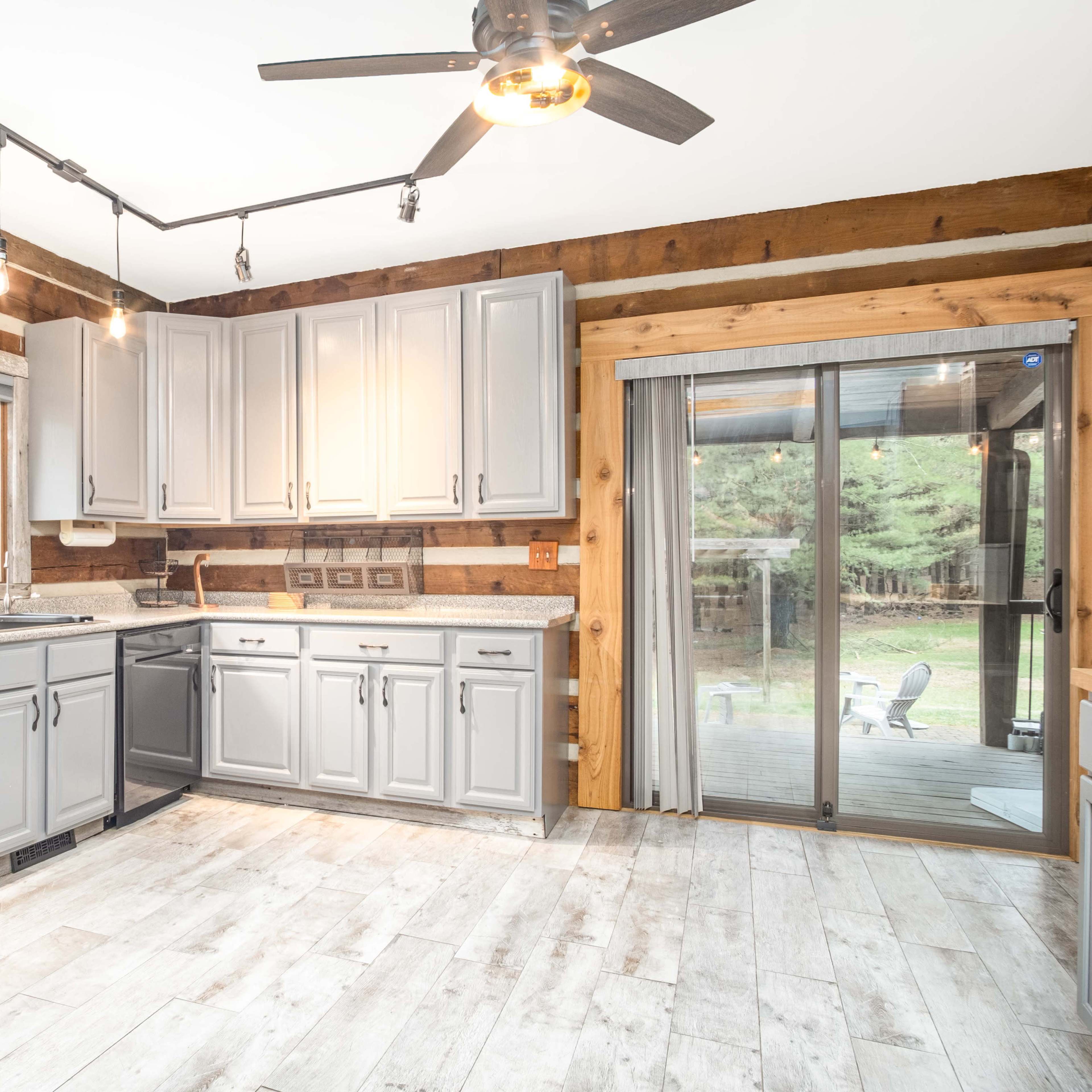 A modern kitchen featuring gray cabinets, stainless steel appliances, and a sliding glass door leading to a patio.