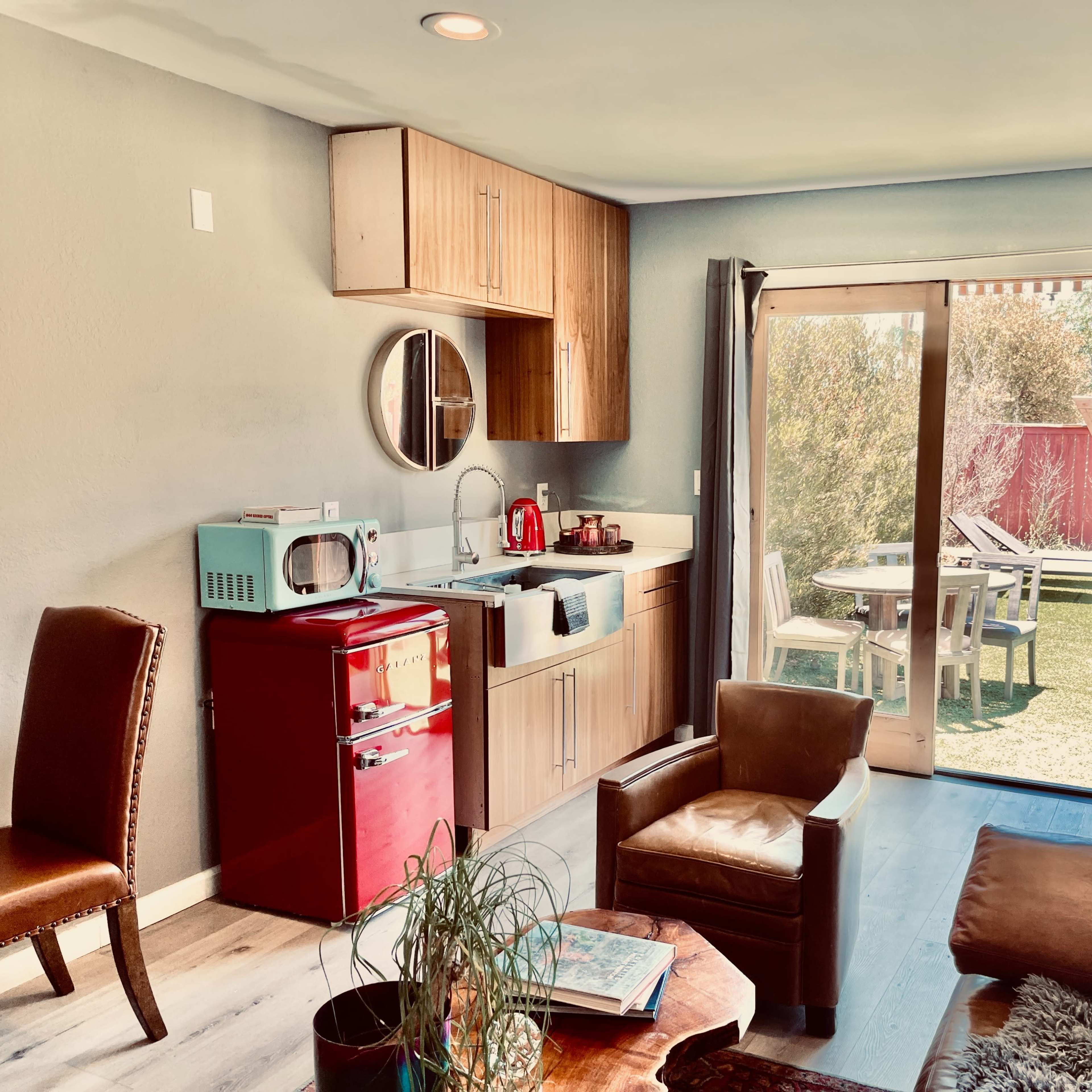 A small kitchen area with modern cabinetry, a table and chairs outside, and a sitting area with leather furniture.