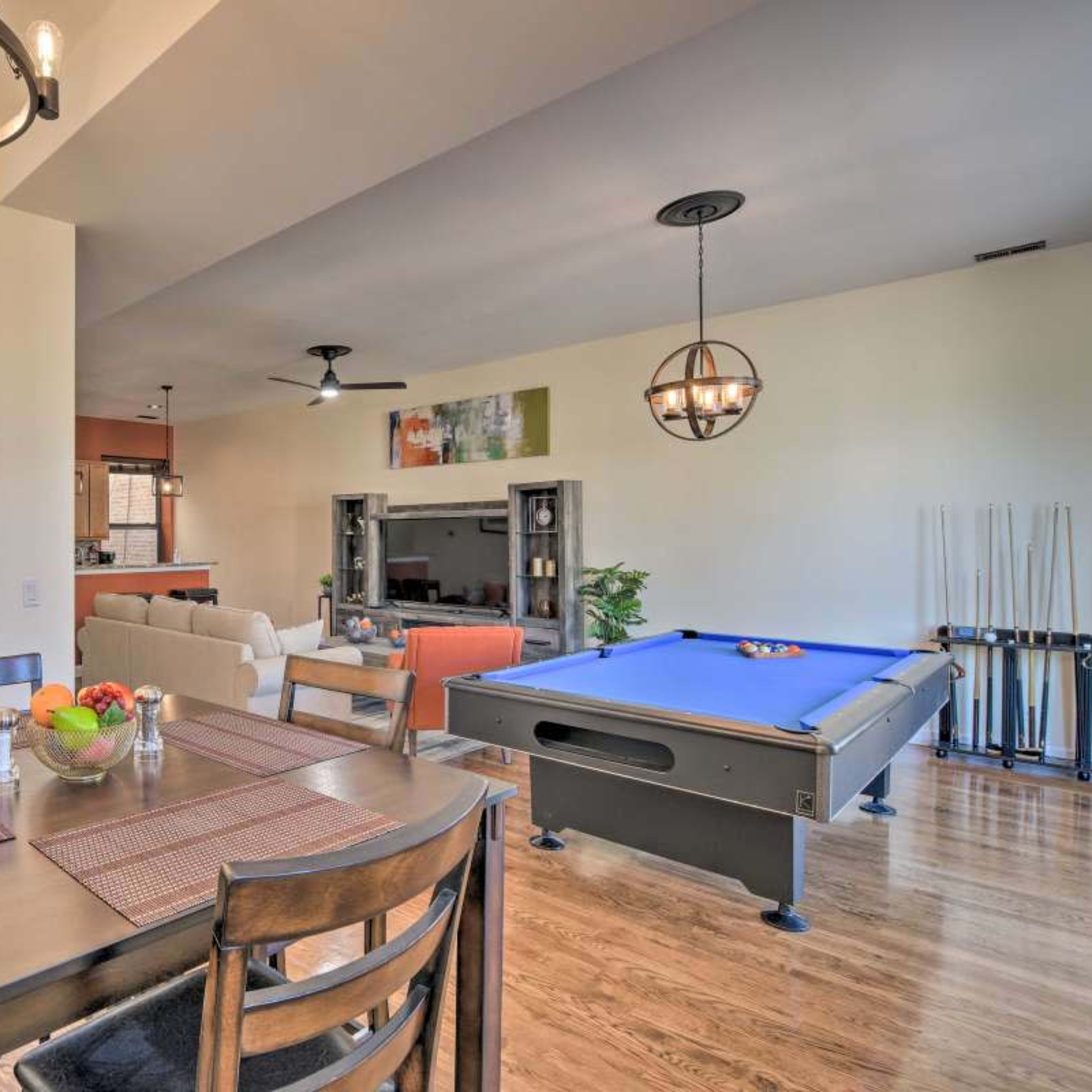 A modern interior featuring a dining table with fruit, a pool table, and a staircase leading to an upper level.