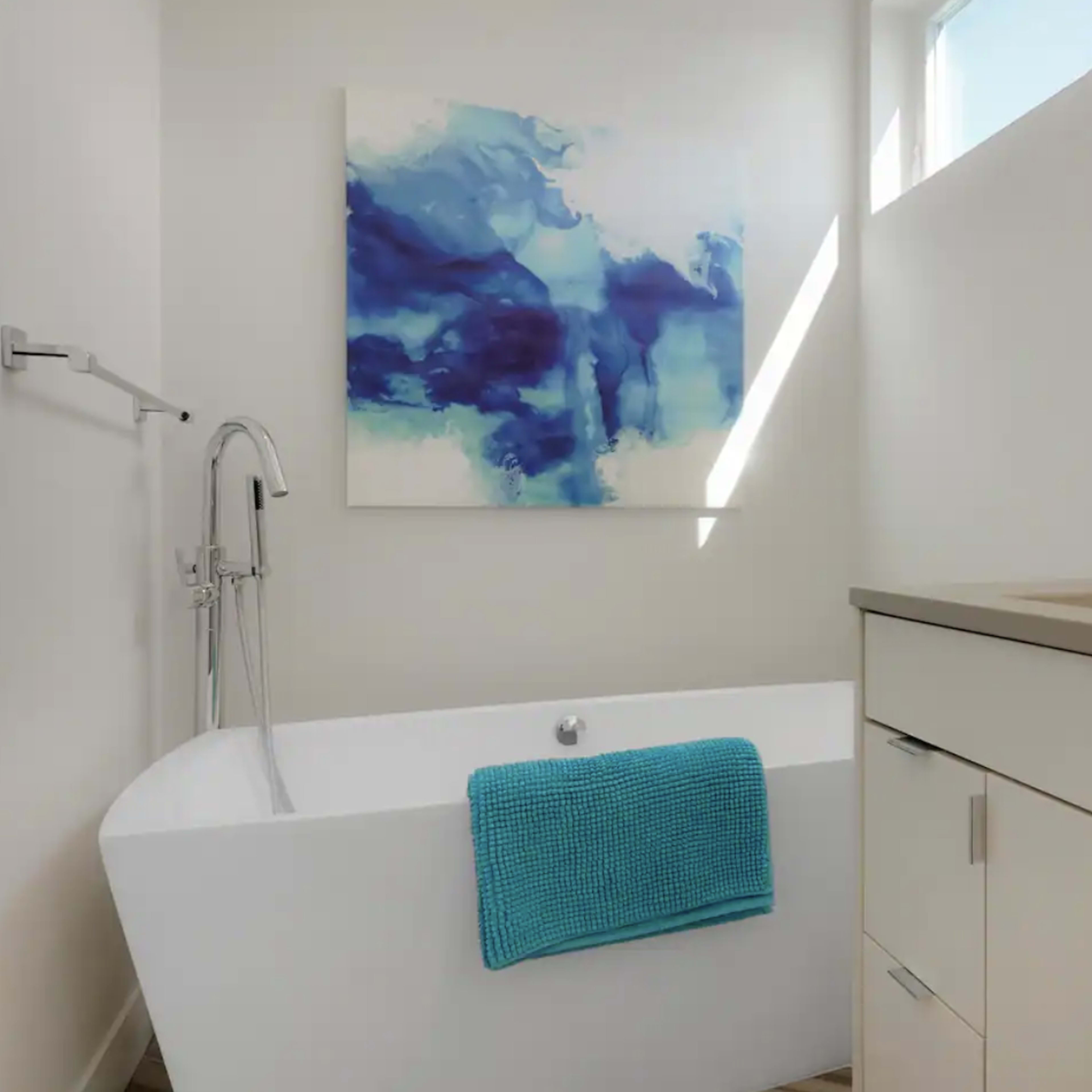 A modern bathroom featuring a freestanding bathtub, a minimalist sink area, and an abstract blue artwork on the wall.
