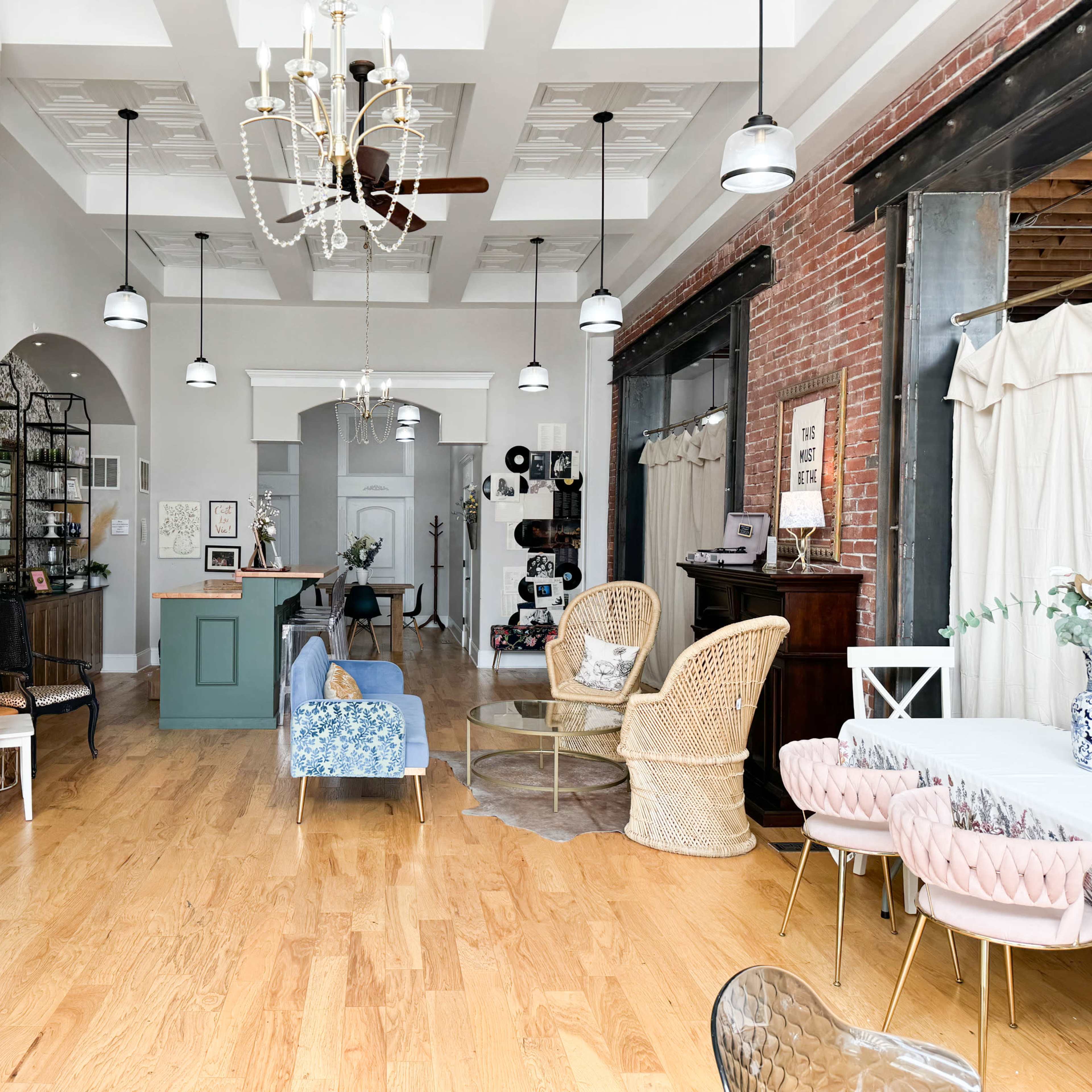 A spacious, well-decorated interior featuring a mix of seating arrangements, decorative plants, and a reception area with a vintage feel.