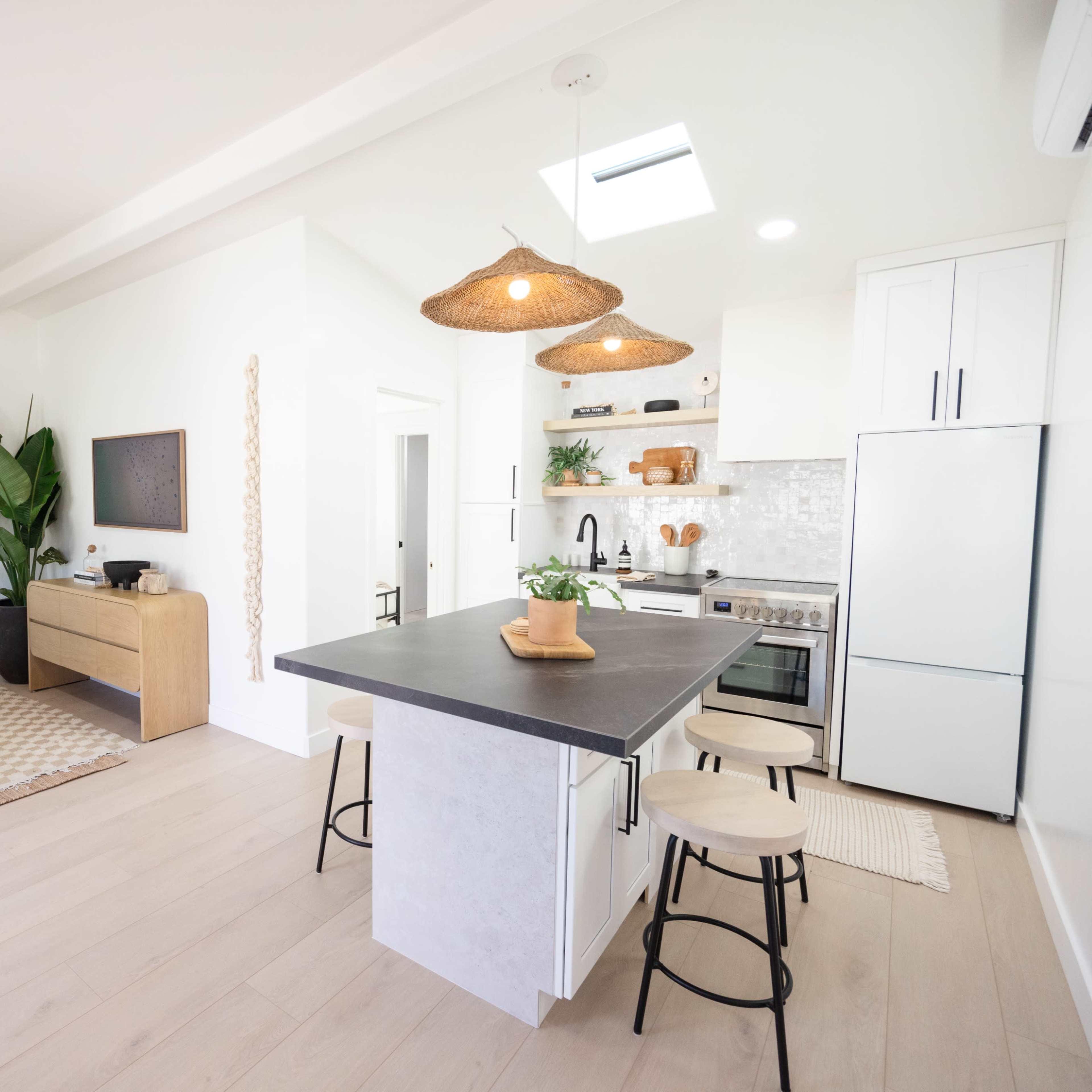 A modern kitchen and living area with a breakfast bar, natural materials, and light-colored furnishings.