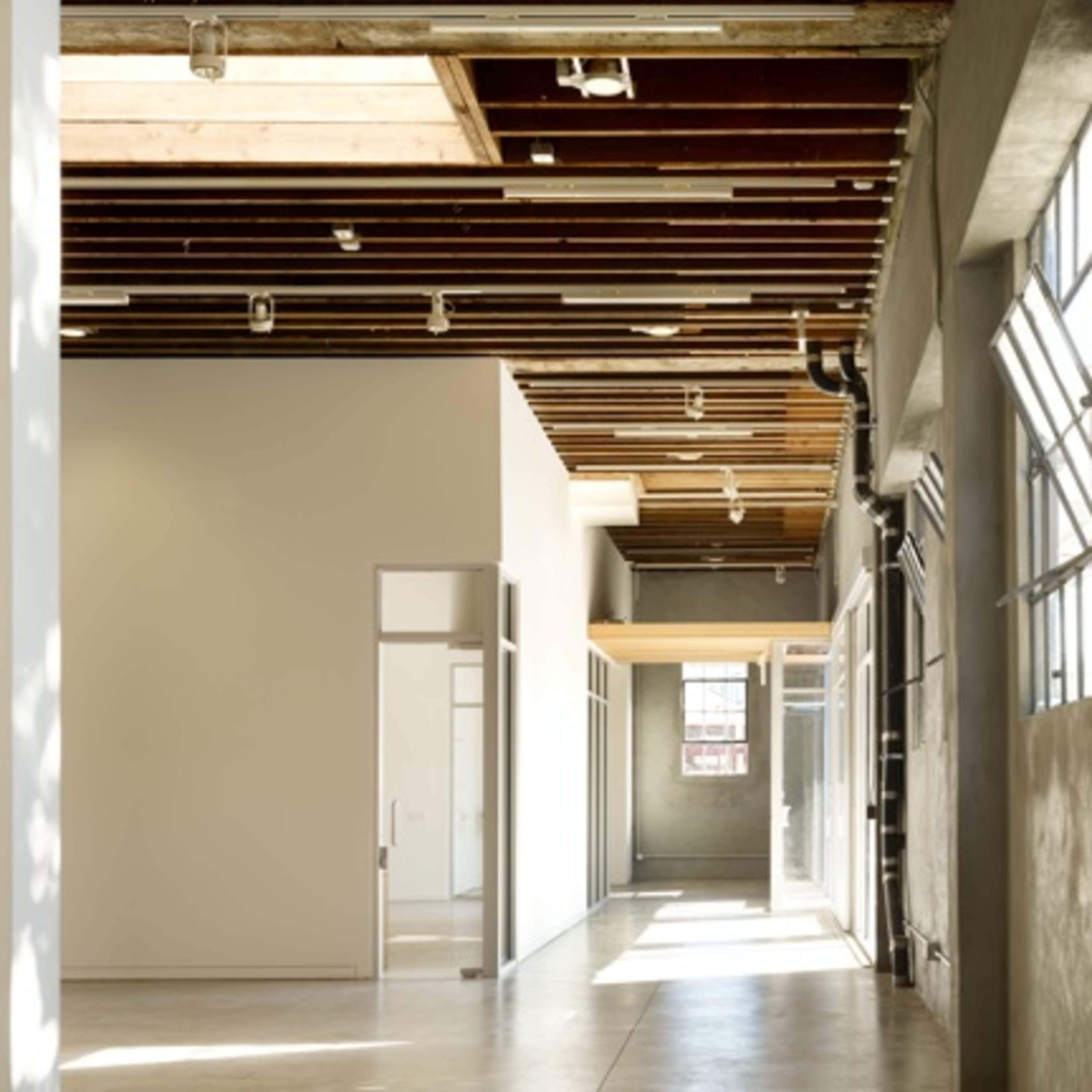 A spacious, modern interior with large windows, exposed beams, and minimalist design features.