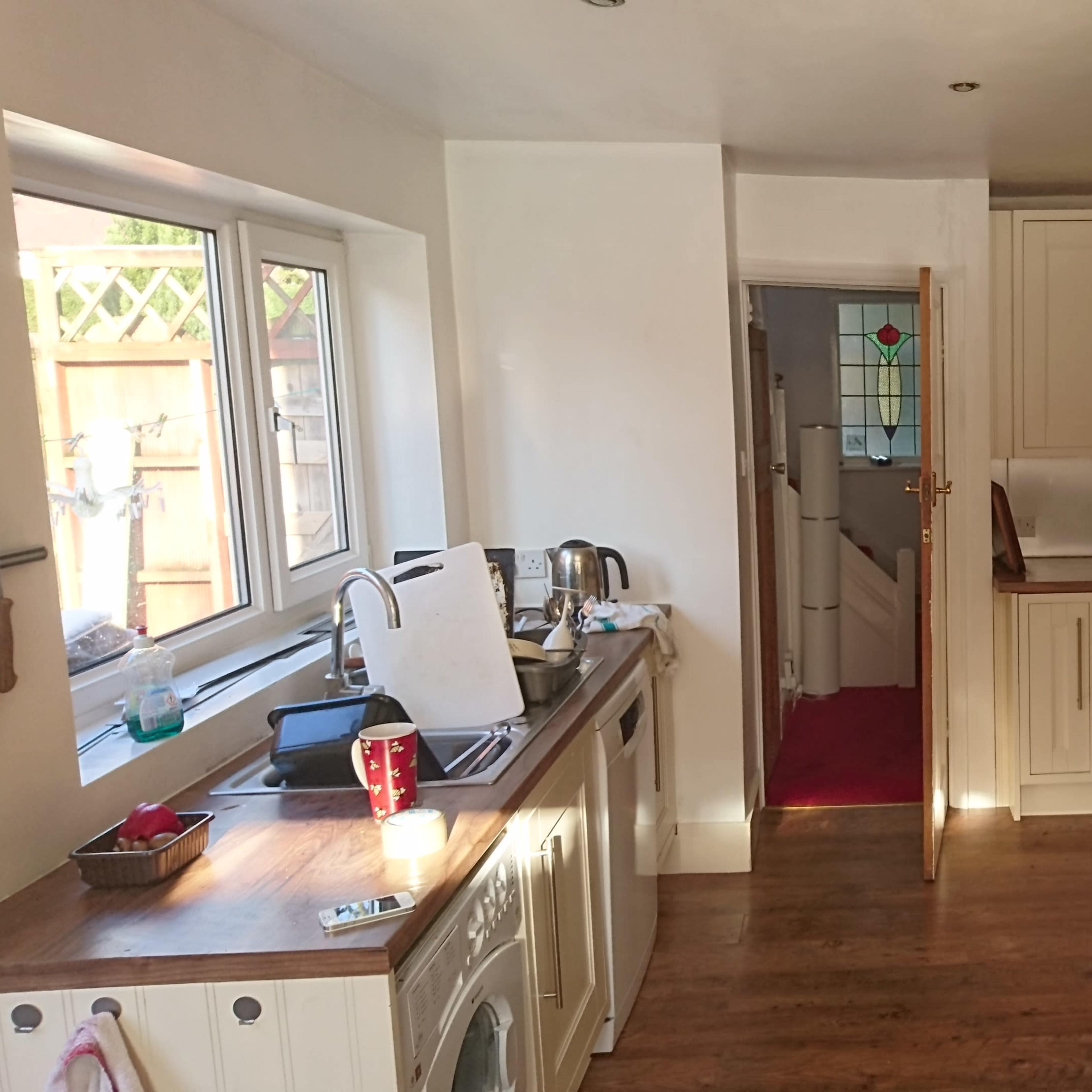 A kitchen features light-colored cabinets, a wooden countertop, and appliances like a microwave and a dishwasher.